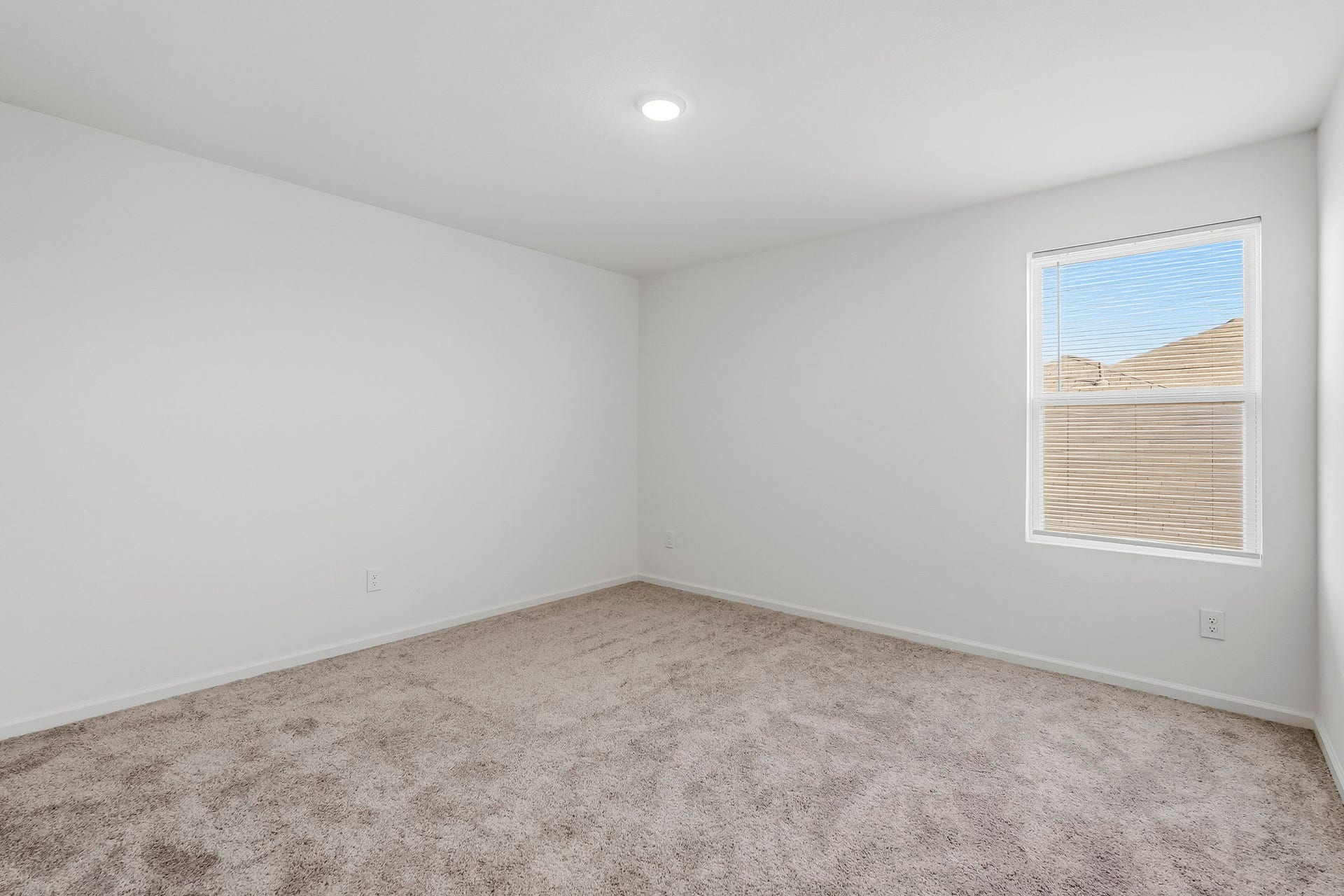 21547 Rolling Streams Drive, New Caney, TX 77357 This bright and inviting bedroom features a spacious layout with crisp white walls, plush neutral carpeting, and a clean, contemporary design. A generously sized window with adjustable blinds allows natural light to fill the space, creating a fresh and airy atmosphere.