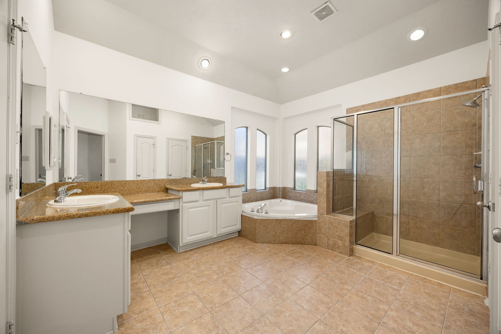 9430 Amethyst Arbor Lane, Katy, TX 77494 Designed as a spa-like retreat, this expansive primary bathroom features a generous double-vanity layout with a built-in makeup station, neutral granite countertops, clean white cabinetry, a deep soaking tub, and a large walk-in shower.