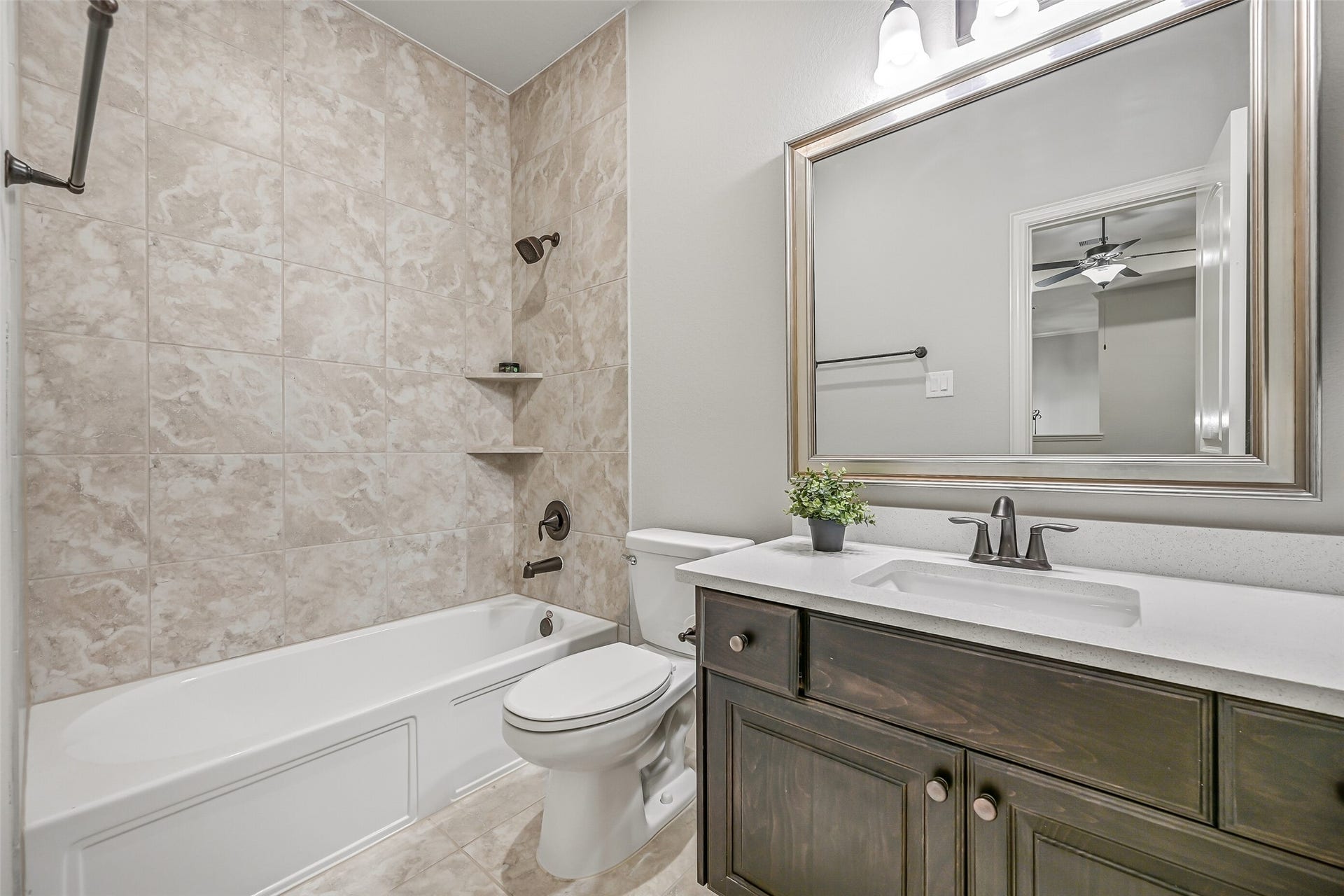 1640 Longwood Glen Lane, Friendswood, TX 77546 Conveniently located off the game room, this full bathroom serves both the game room & adjoining secondary bedroom. Features include a quartz-topped vanity, rectangular sink, stained wood cabinetry, framed mirror & tub/shower combination with a tiled surround.