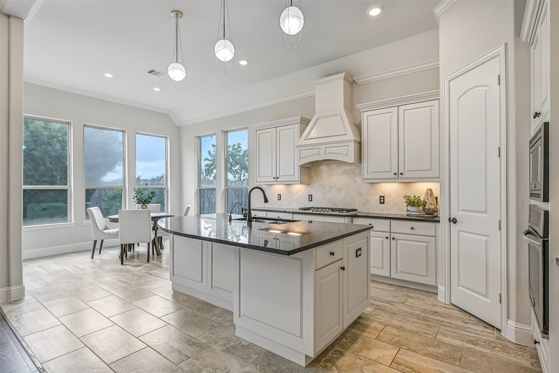 1640 Longwood Glen Lane, Friendswood, TX 77546 From the kitchen, enjoy a lovely view into the sunlit breakfast room! The 5-burner Frigidaire gas cooktop sits beneath a custom vent hood, framed by a herringbone brick backsplash, granite countertops & undercabinet task lighting.
