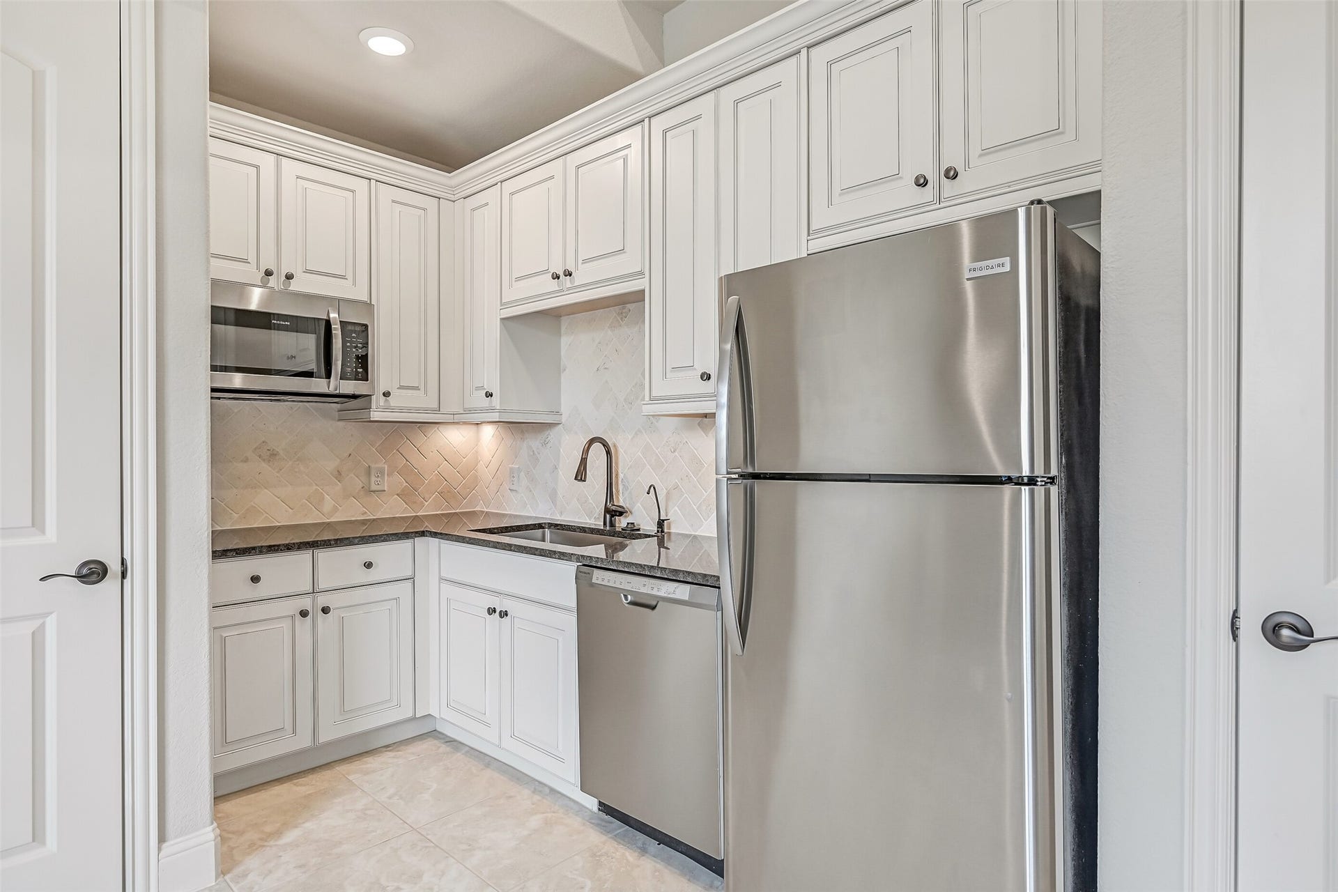1640 Longwood Glen Lane, Friendswood, TX 77546 Don't let the word kitchenette fool you! This well-equipped space features granite countertops, white raised-panel cabinetry, a herringbone tile backsplash, undercabinet lighting, stainless Frigidaire dishwasher, microwave & full-size refrigerator. A deep single-basin sink & pantry add even more functionality.