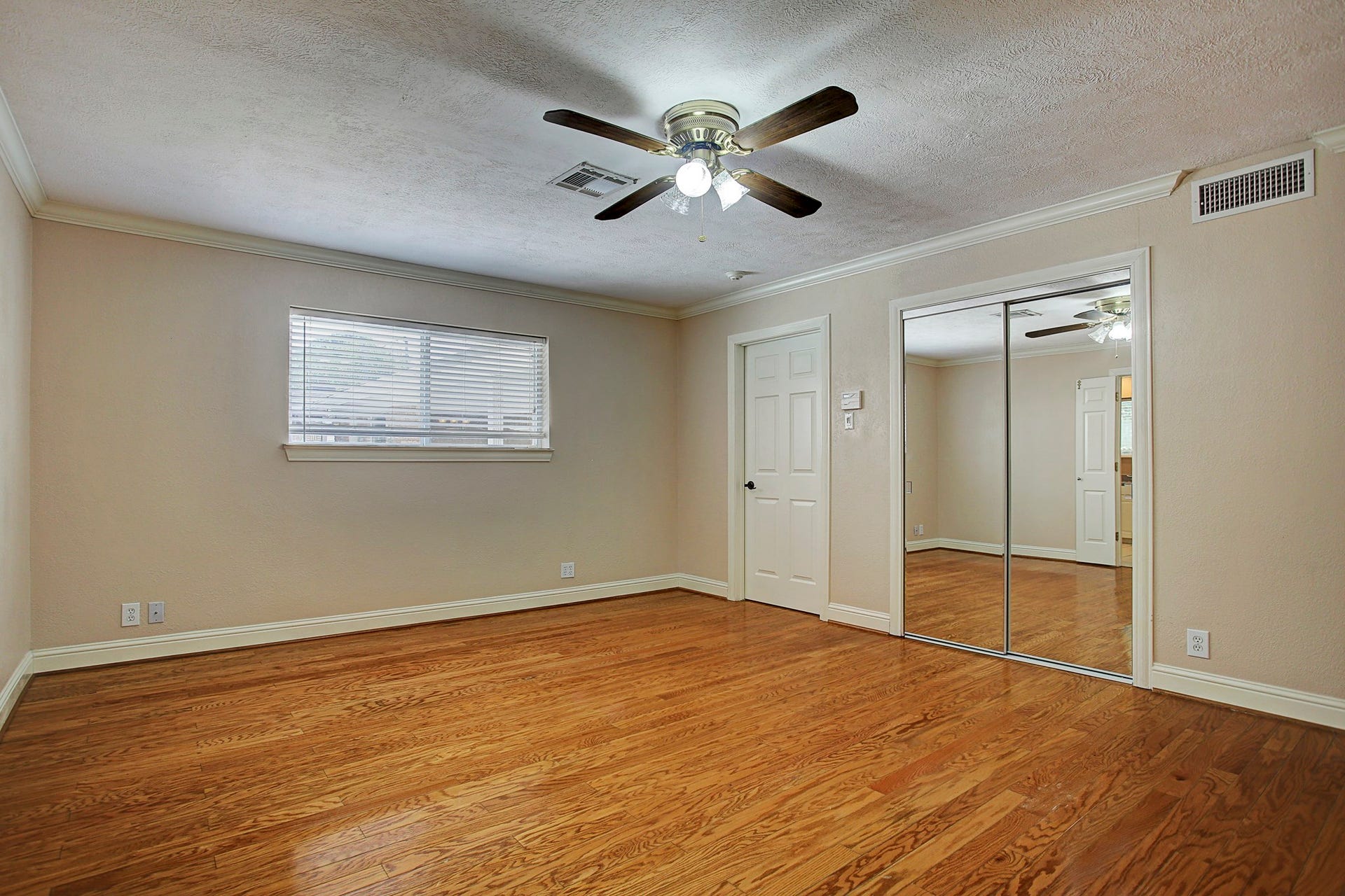 A secondary bedroom with mirrored closet doors, crown molding, and room to make yourself comfortable.