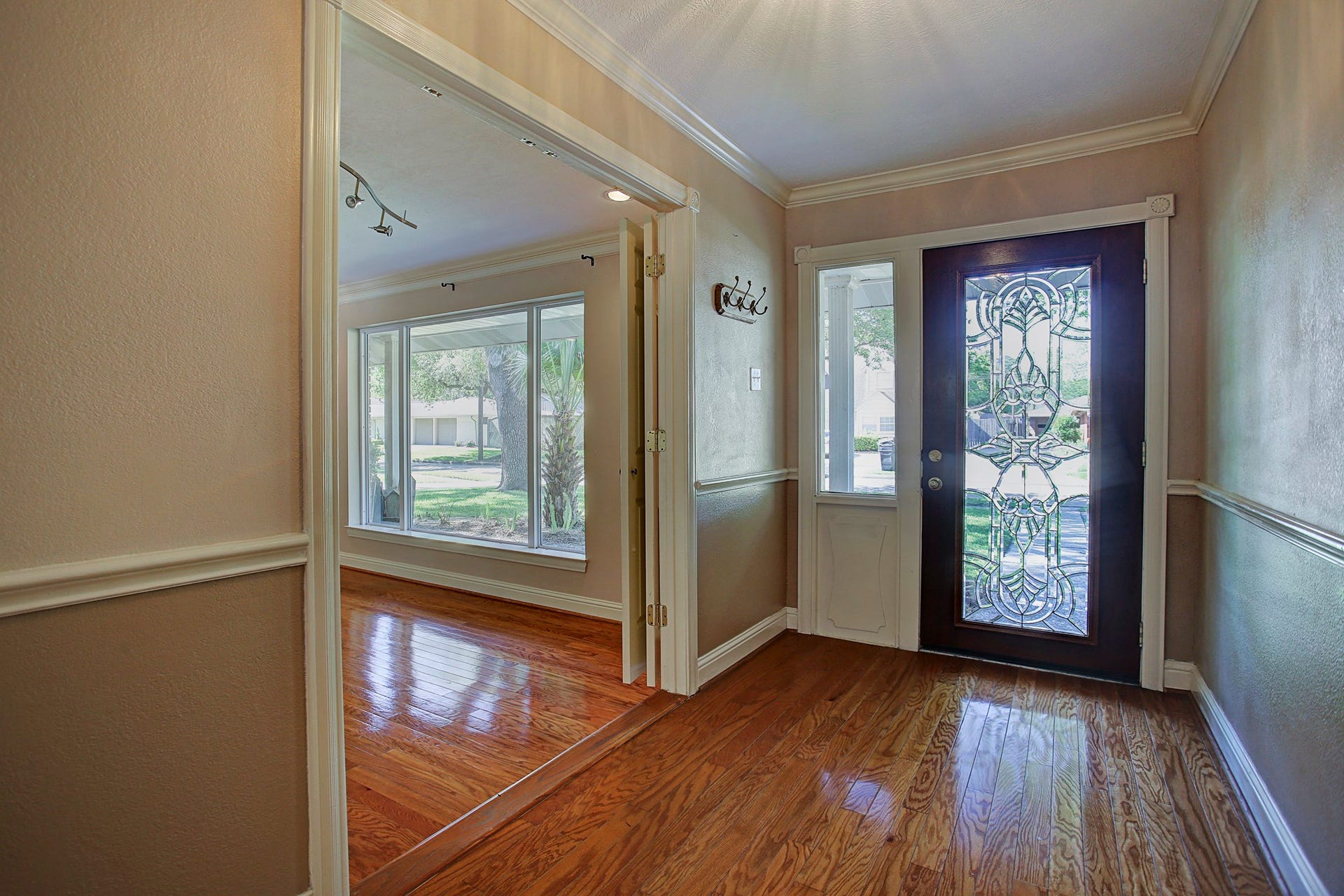 Hardwood floors, a decorative glass door, and a glimpse of the light-filled front living room make a warm first impression.