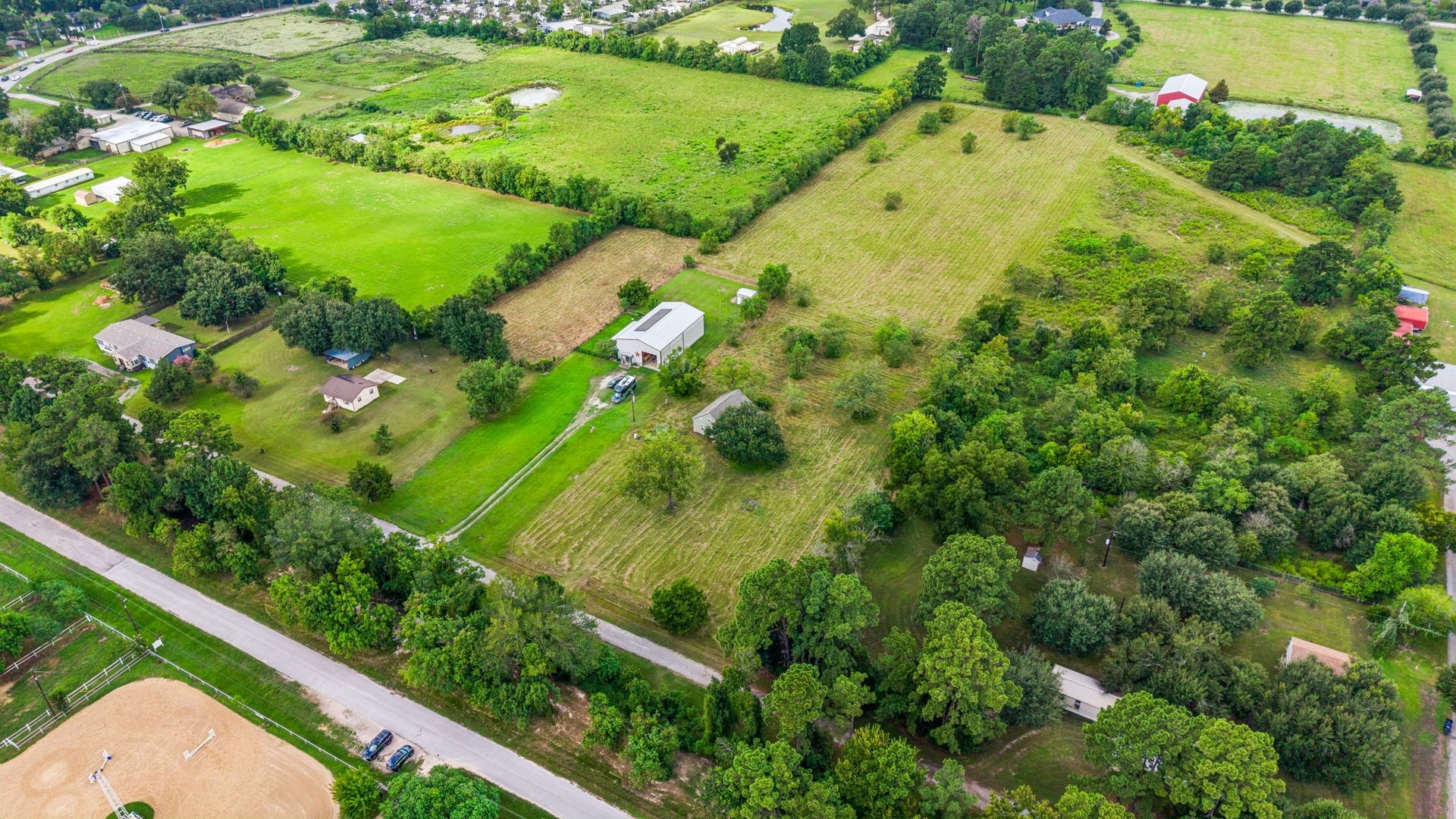10534 Hufsmith Road, Tomball, TX 77375 High-altitude angle drone view showing direct, accessible road frontage and expansive acreage depth. The open field and flexible plot design allow seamless access for large commercial trucks, trailers, horses, or constructing massive detached workshops.