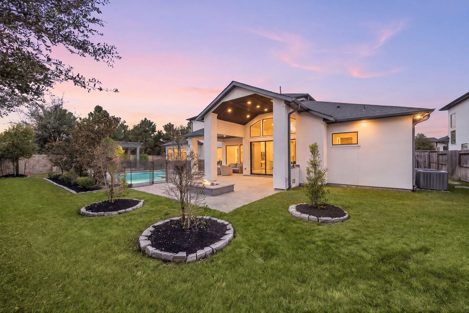 27927 Indigo Ridge Drive, Fulshear, TX 77441 Gorgeous backyard showcasing manicured landscaping, a spacious lawn, and beautiful evening views of the home.