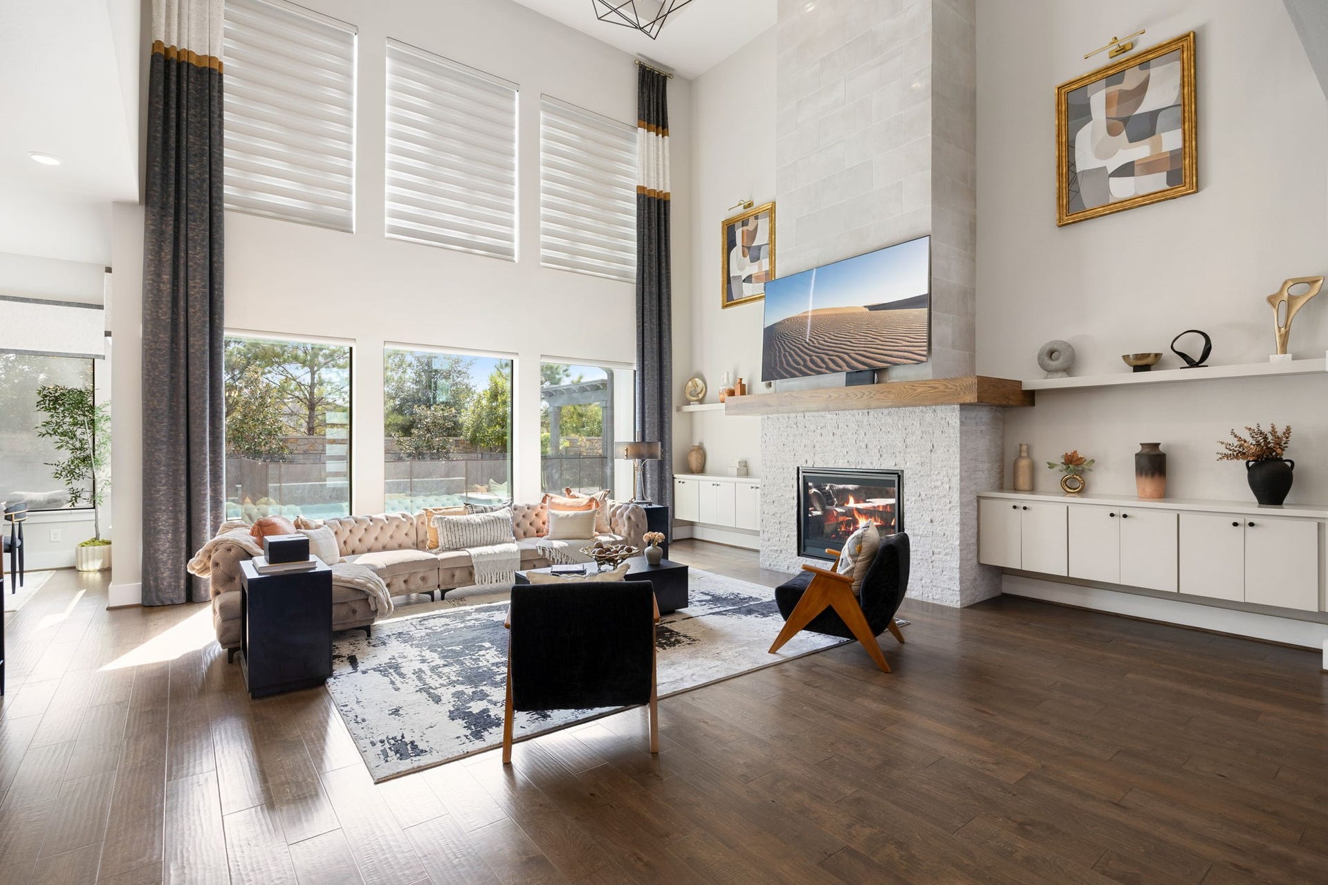 27927 Indigo Ridge Drive, Fulshear, TX 77441 Enjoy an abundance of natural light in this spacious living area with beautiful views of the backyard. Additional upgrades include floating cabinetry, shelving for storage and decor, tray ceiling, and custom drapery and lighting.
