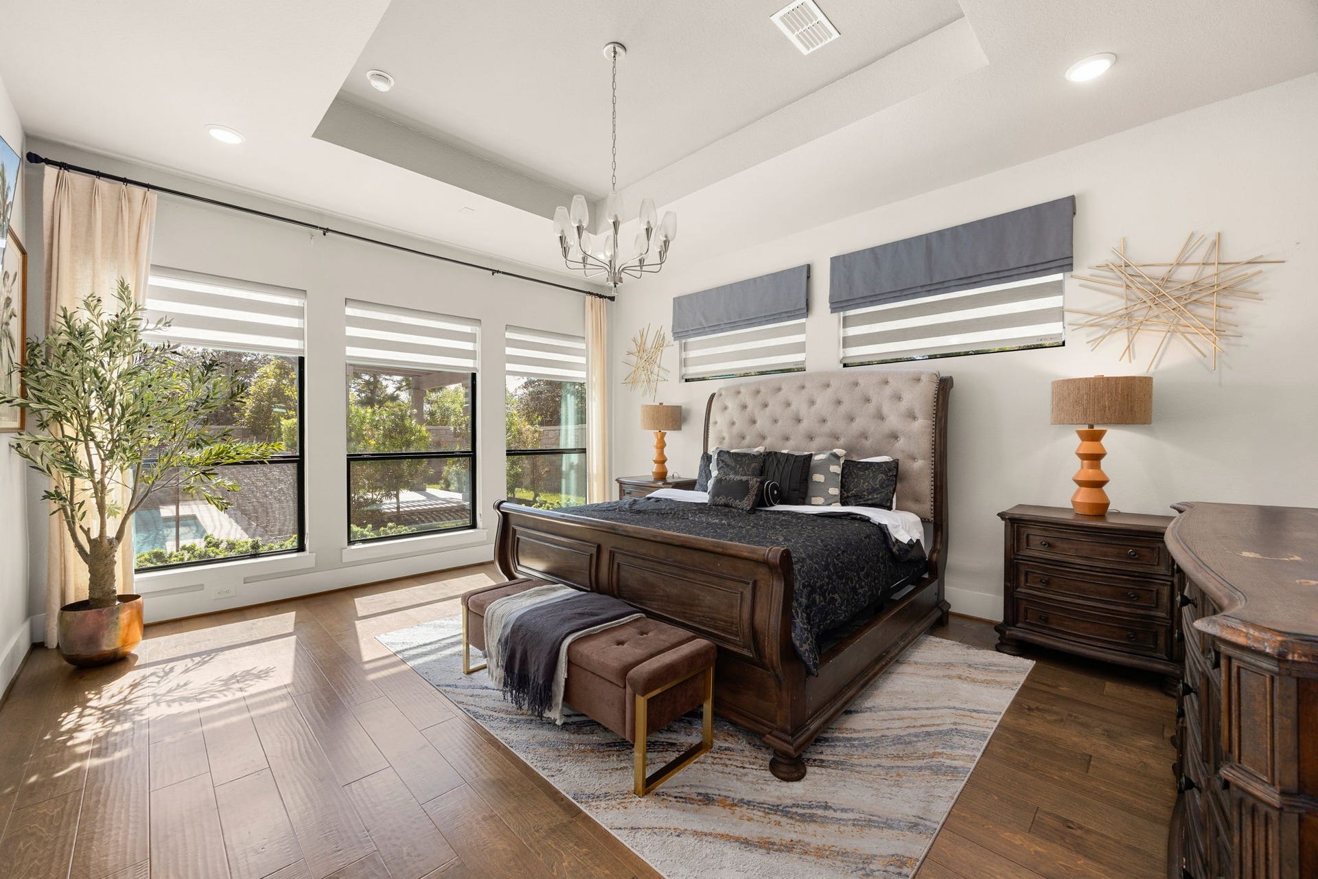 27927 Indigo Ridge Drive, Fulshear, TX 77441 Spacious primary suite featuring a tray ceiling, large windows, custom shades, engineered wood floors, and a relaxing atmosphere.