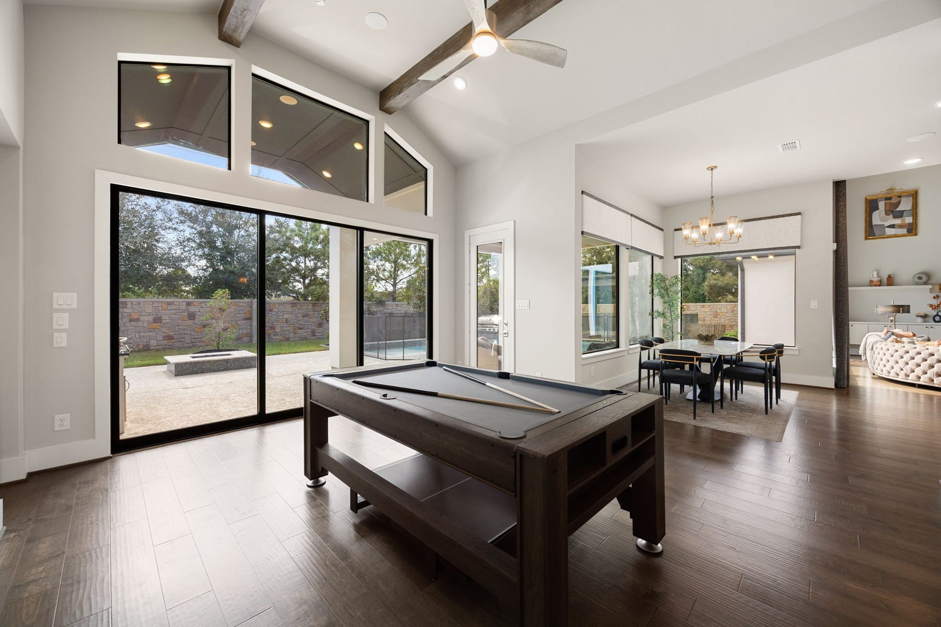 27927 Indigo Ridge Drive, Fulshear, TX 77441 Spacious downstairs game room area with soaring ceilings and large sliding glass doors that overlook the backyard and connect to the kitchen and main living areas.