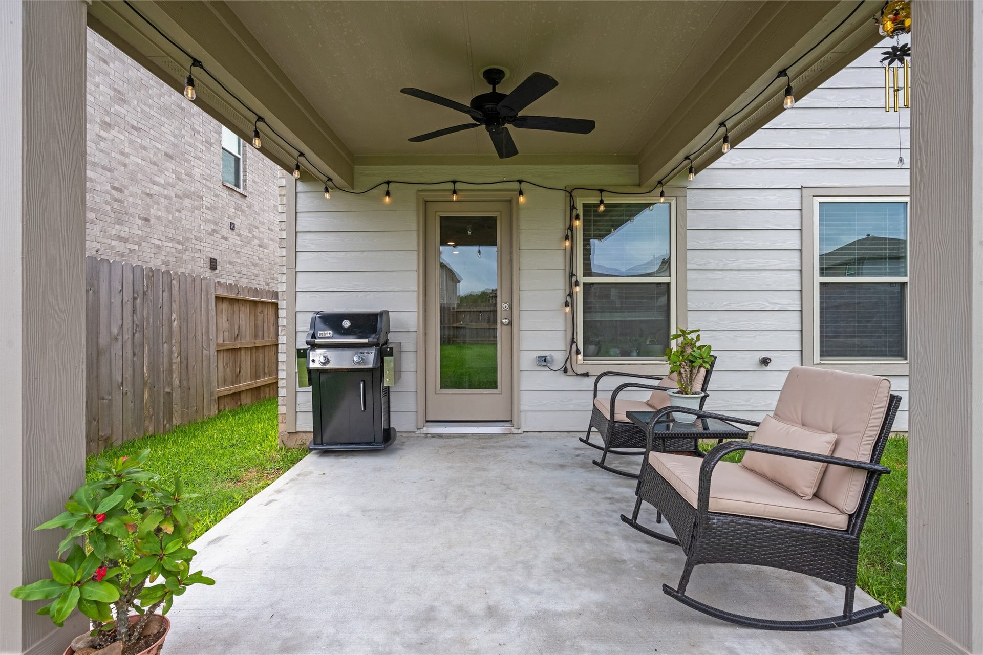2873 Shimmer Edge Drive, Katy, TX 77493 Spacious covered patio designed for outdoor living and entertaining, complete with a ceiling fan and string lighting for added ambiance.