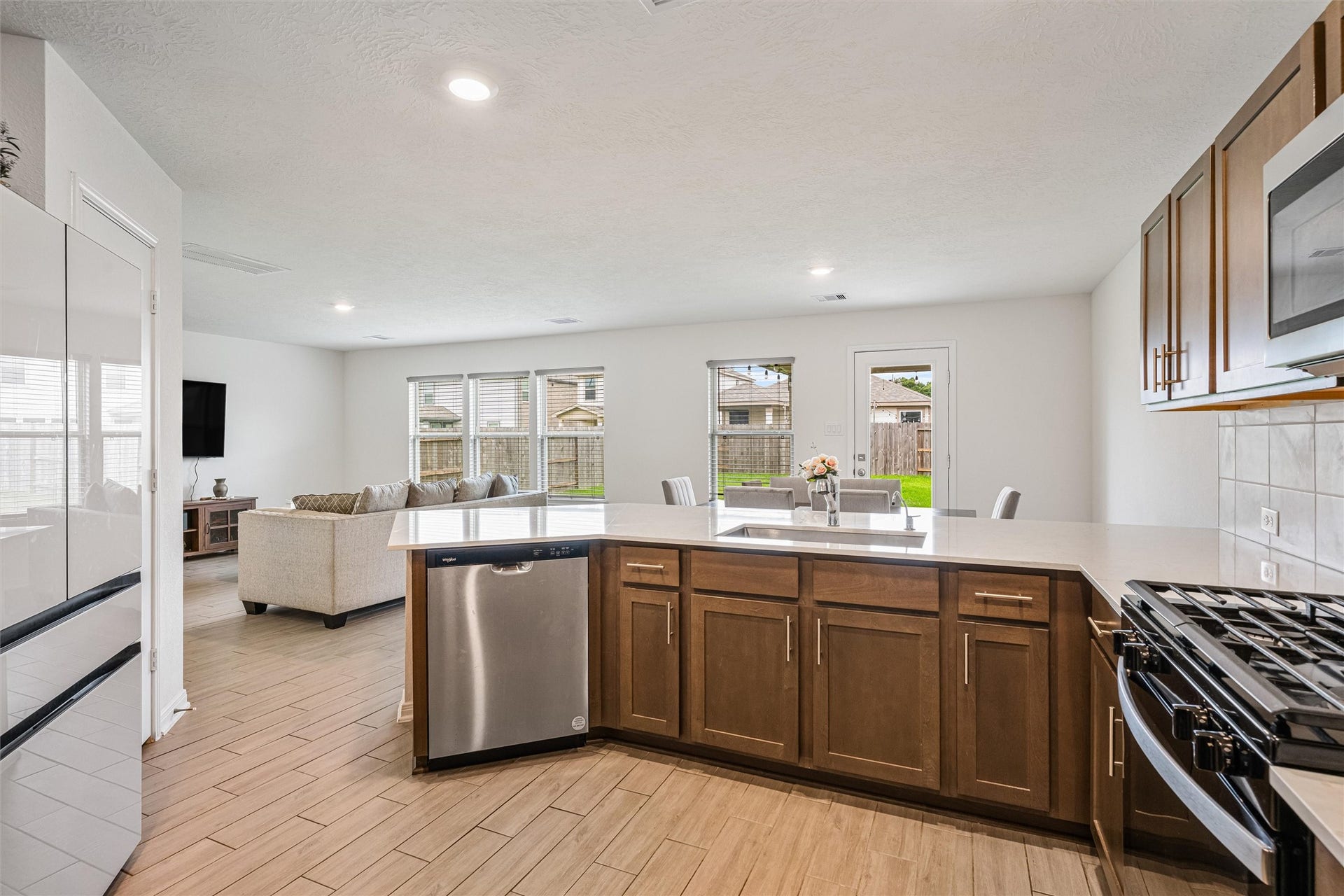 2873 Shimmer Edge Drive, Katy, TX 77493 This angle highlights the seamless connection between the kitchen, dining, and family room, ideal for entertaining. The large peninsula with undermount sink and dishwasher offers both workspace and gathering space, while the open sightlines extend to the wall of windows in the family room.
