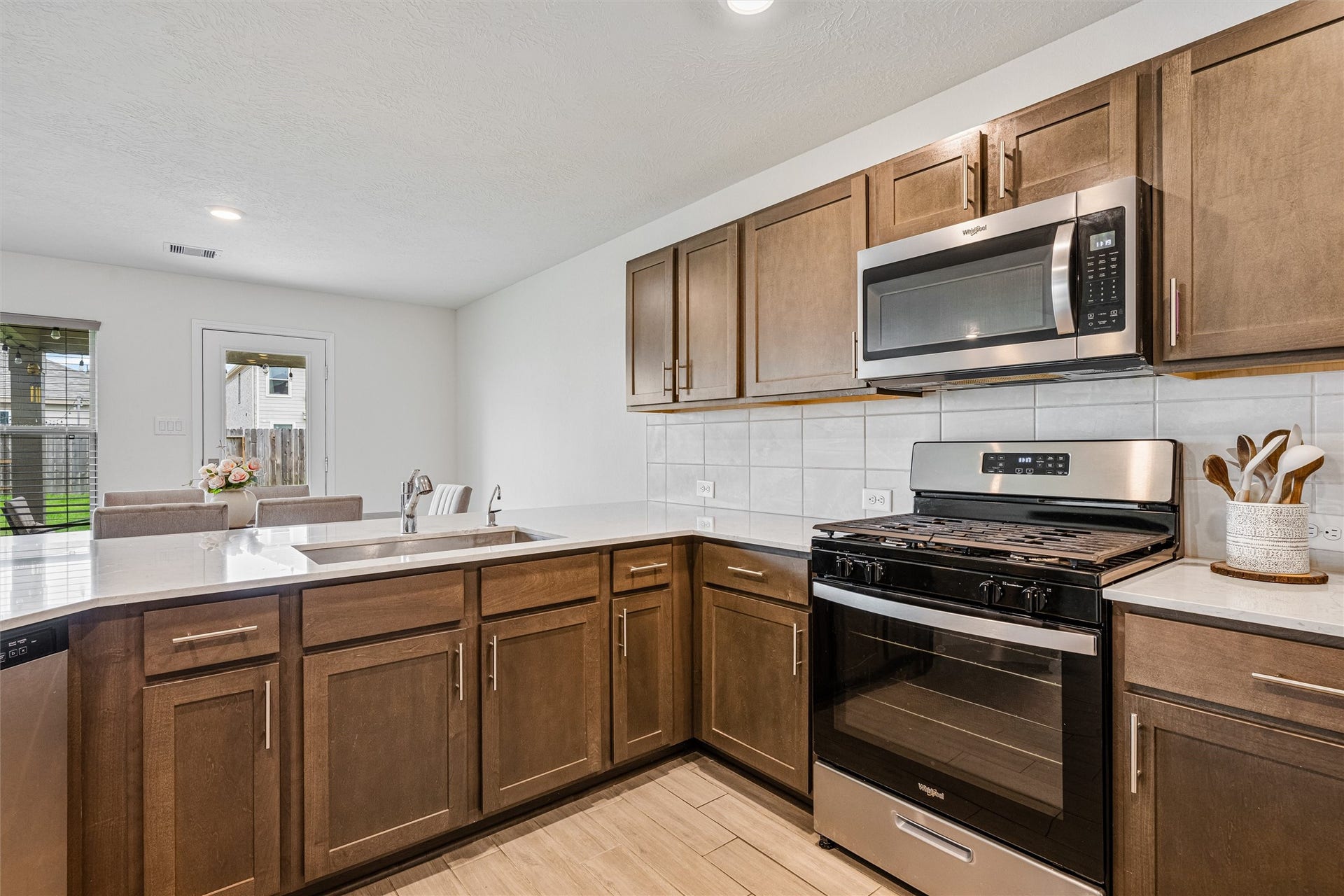 2873 Shimmer Edge Drive, Katy, TX 77493 Detailed view of the cooking zone featuring a gas range, built-in microwave, and surrounding cabinetry for convenient storage. The light tile backsplash and generous counter space enhance both style and everyday functionality.