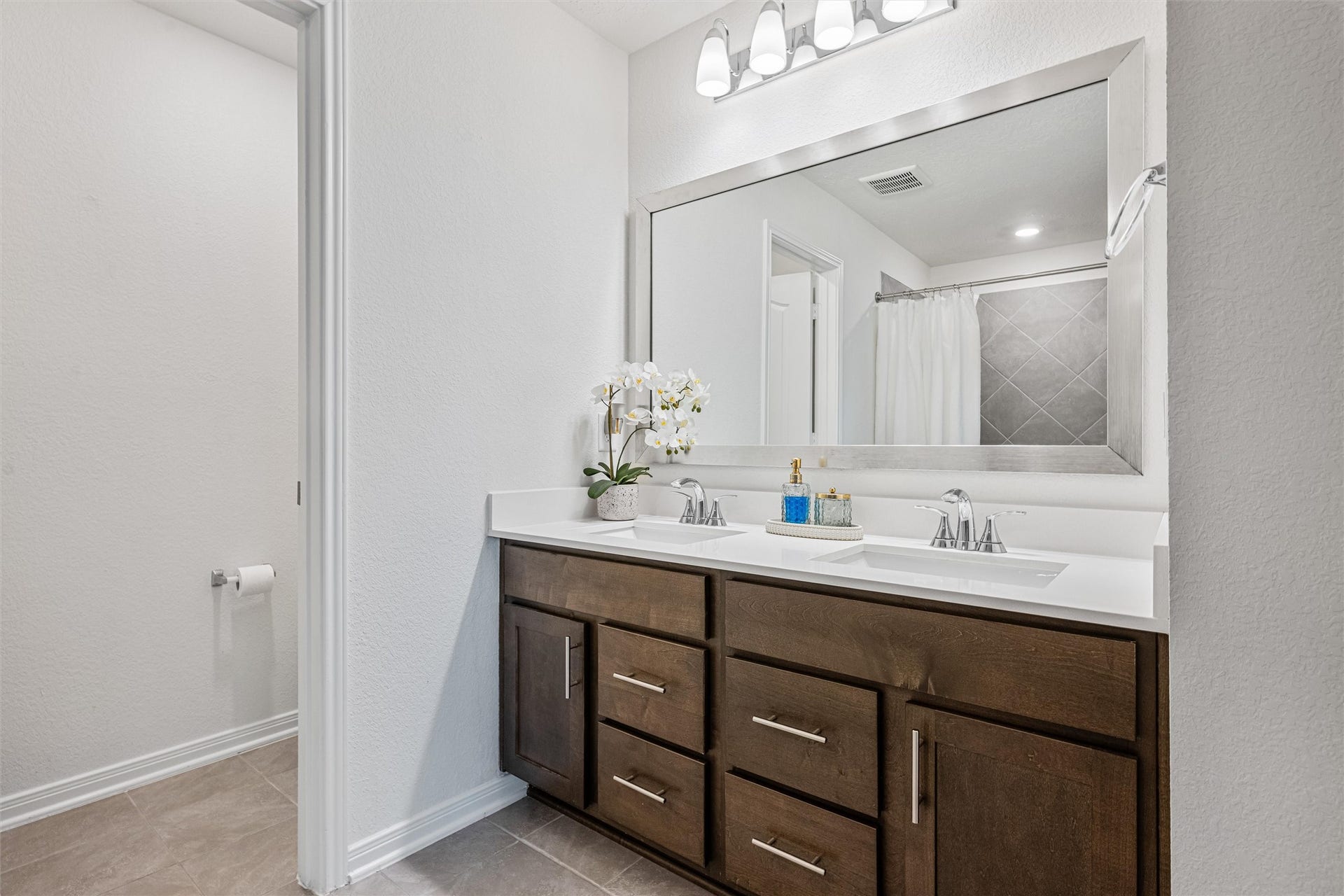2873 Shimmer Edge Drive, Katy, TX 77493 Well-appointed primary bathroom featuring a spacious dual-sink vanity with sleek quartz countertops, undermount sinks, and modern fixtures. A large framed mirror and updated lighting enhance both style and functionality, while abundant cabinetry provides excellent storage.