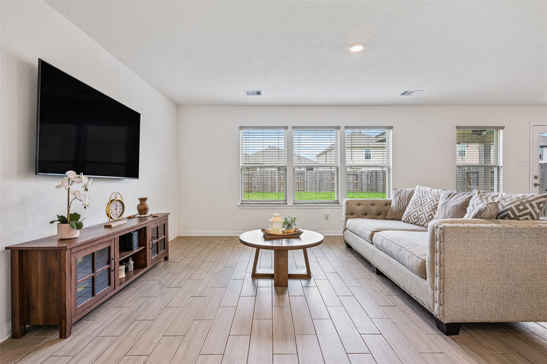 2873 Shimmer Edge Drive, Katy, TX 77493 Spacious family room highlighted by a wall of windows that fills the space with natural light and offers peaceful backyard views. The open layout provides ample room for furniture placement, while the neutral tones and wood-look tile flooring create a versatile backdrop.