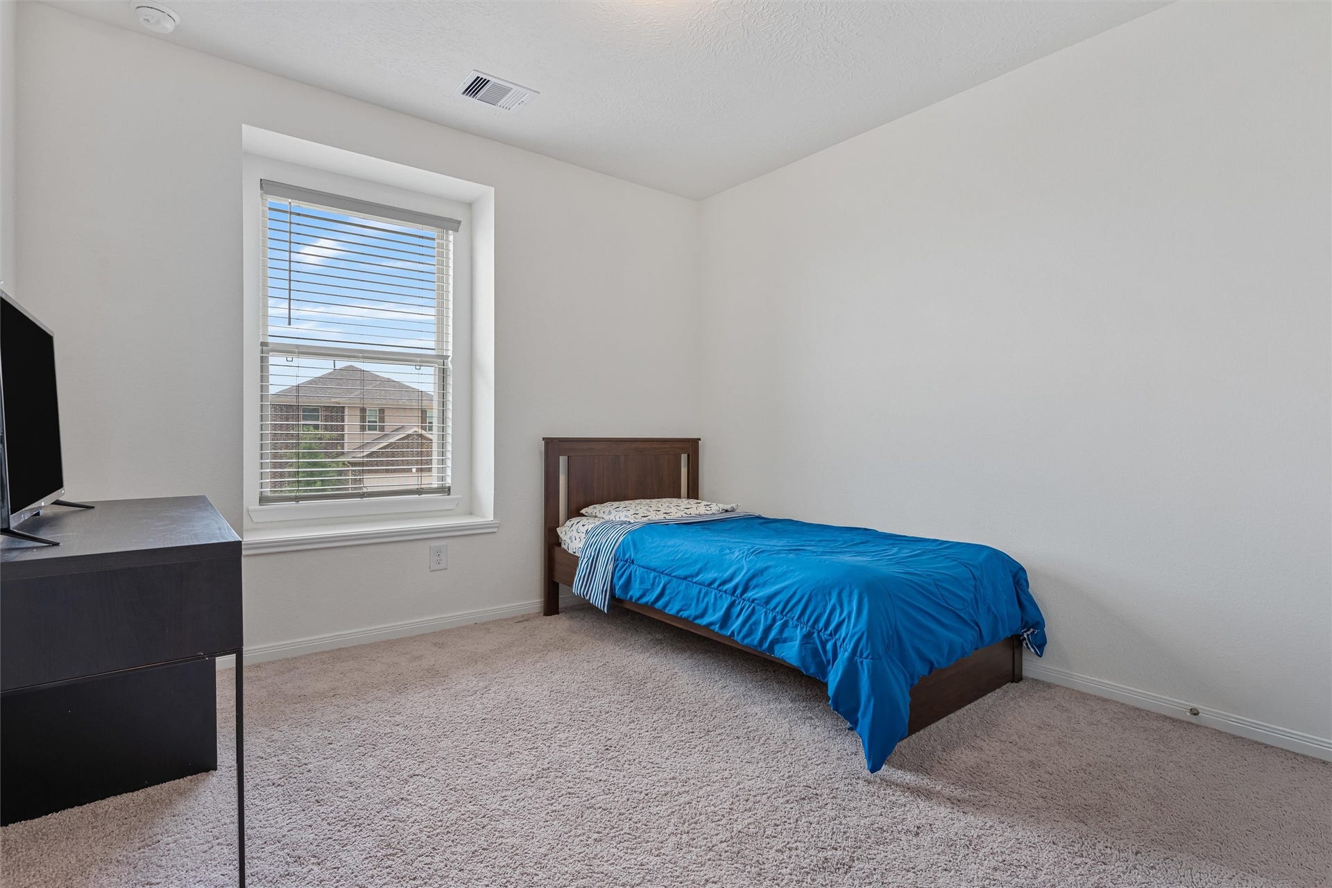 2873 Shimmer Edge Drive, Katy, TX 77493 Additional secondary bedroom offering comfortable accommodations with plush carpet, neutral tones, and a large window for natural light. The room provides a cozy yet spacious setting, perfect for guests or family members.