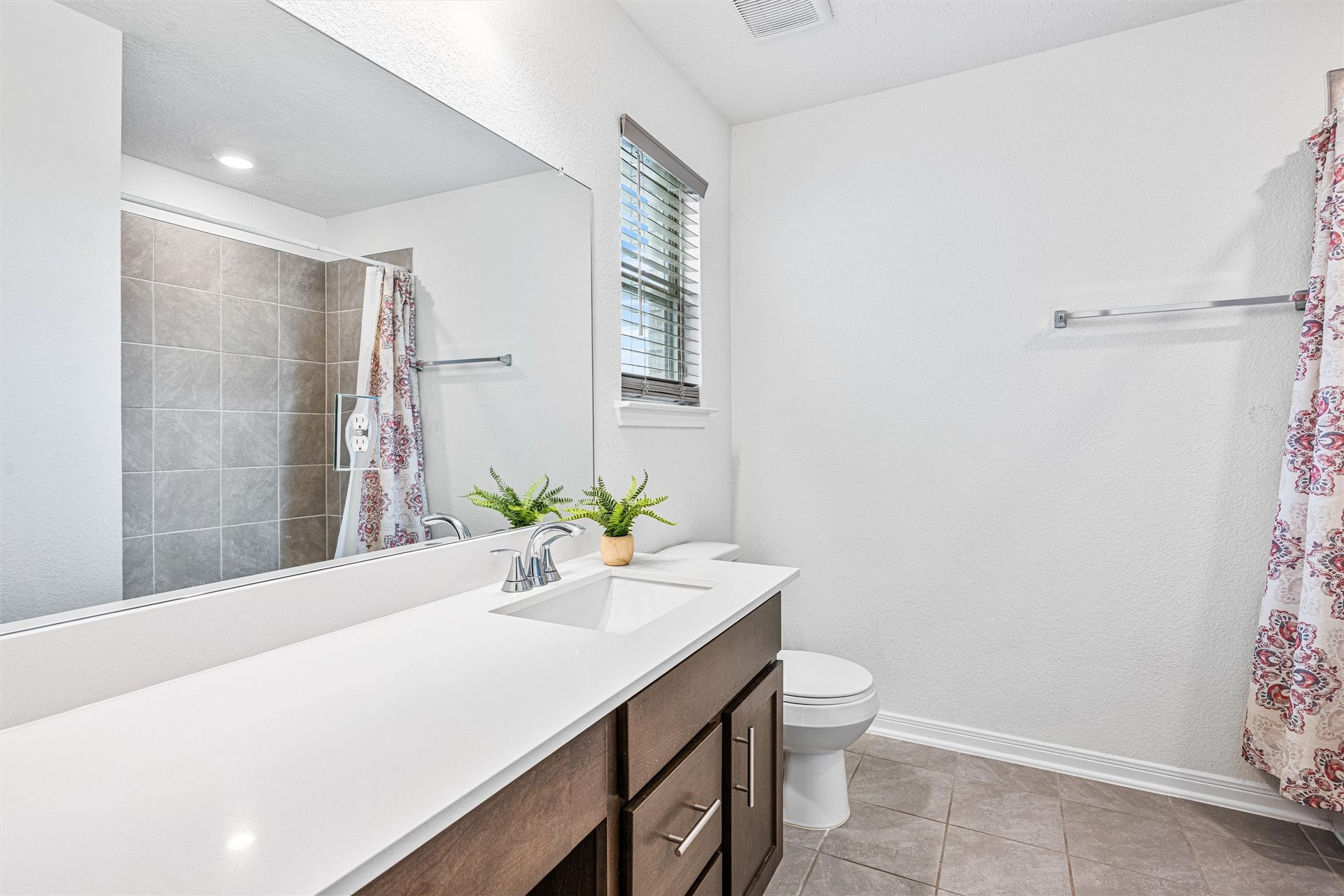 2873 Shimmer Edge Drive, Katy, TX 77493 Well-appointed secondary bathroom featuring a sleek vanity with quartz countertop, undermount sink, and modern fixtures. A large framed mirror enhances the sense of space, while the tub/shower combination with tile surround offers both style and practicality.