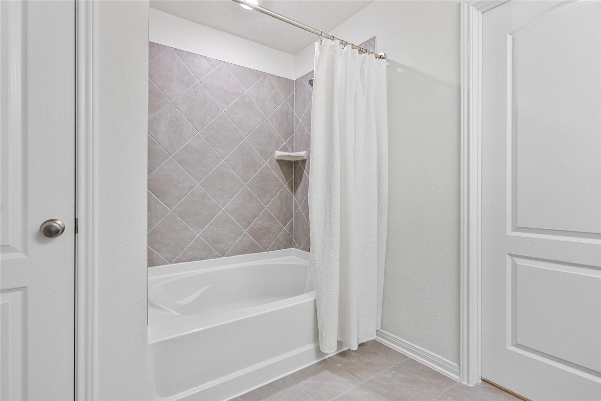 2873 Shimmer Edge Drive, Katy, TX 77493 Relaxing tub/shower combination with tile surround and built-in shelving for added convenience. The clean lines and neutral finishes create a spa-like atmosphere, ideal for both quick routines and leisurely baths.