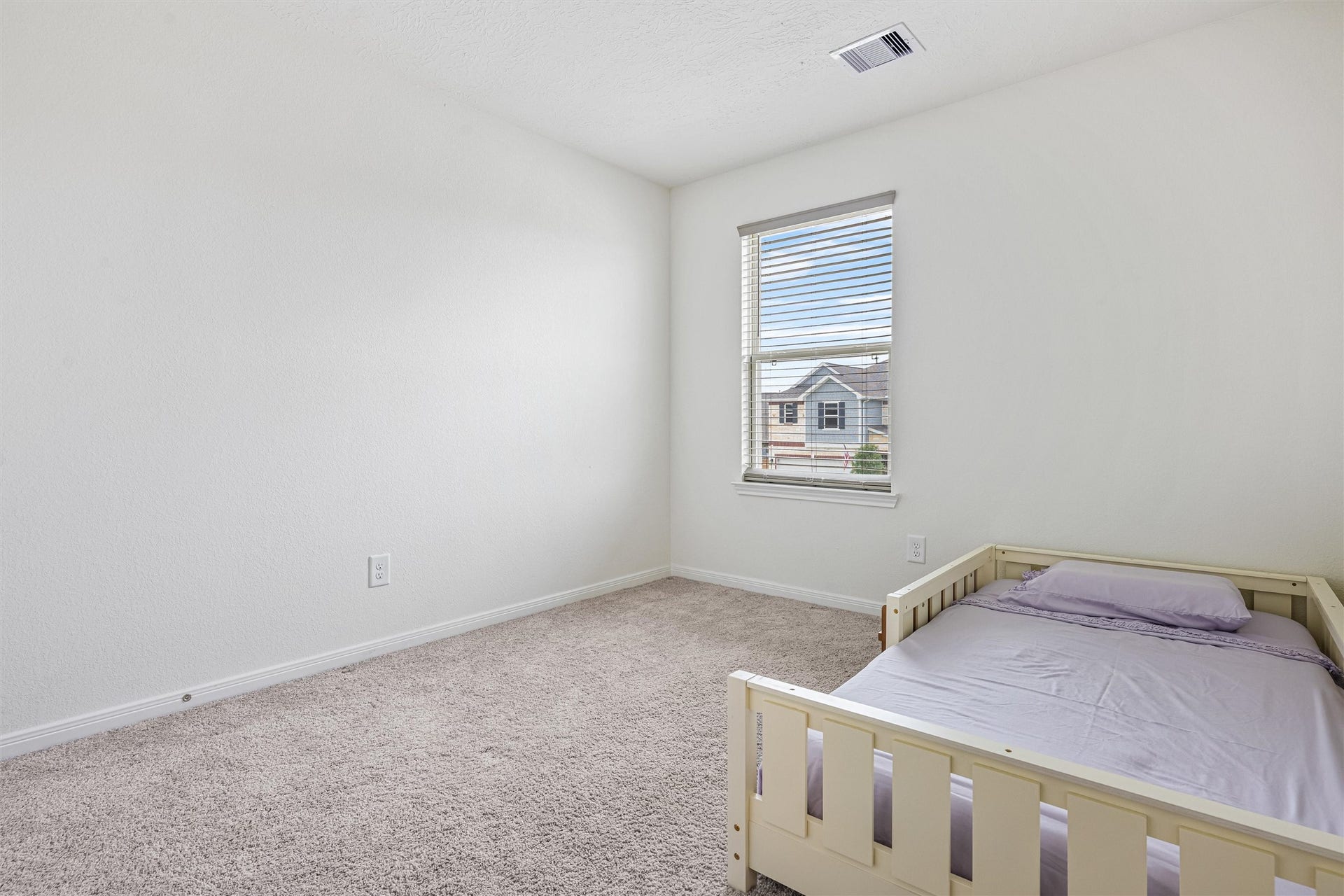 2873 Shimmer Edge Drive, Katy, TX 77493 Bright and spacious secondary bedroom featuring plush carpet, neutral paint tones, and a large window that fills the room with natural light while offering neighborhood views. The layout provides ample space for furniture placement, making it ideal for a bedroom, nursery, or flex space.