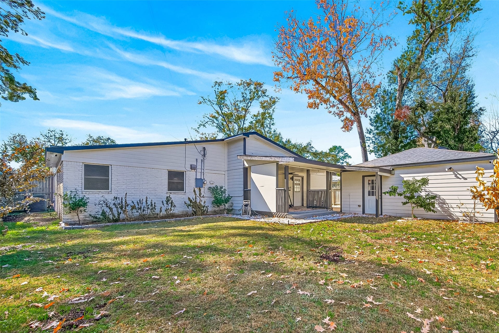 10054 Cedardale Drive, Houston, TX 77055 Single-story home with a spacious backyard, mature trees, and a covered patio area.