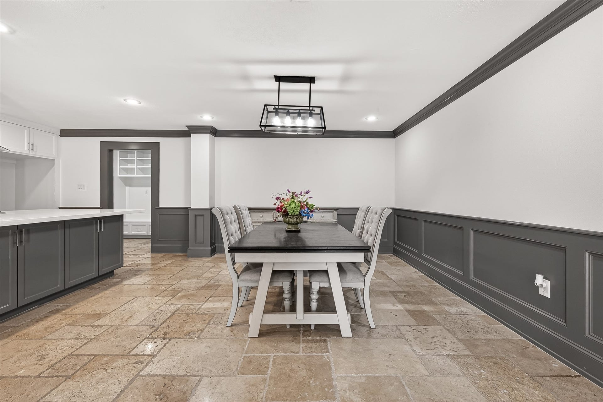 10054 Cedardale Drive, Houston, TX 77055 This dining area features elegant wainscoting and a modern light fixture. The room is complemented by a sleek, dark dining table and chairs, set on polished stone tiles.