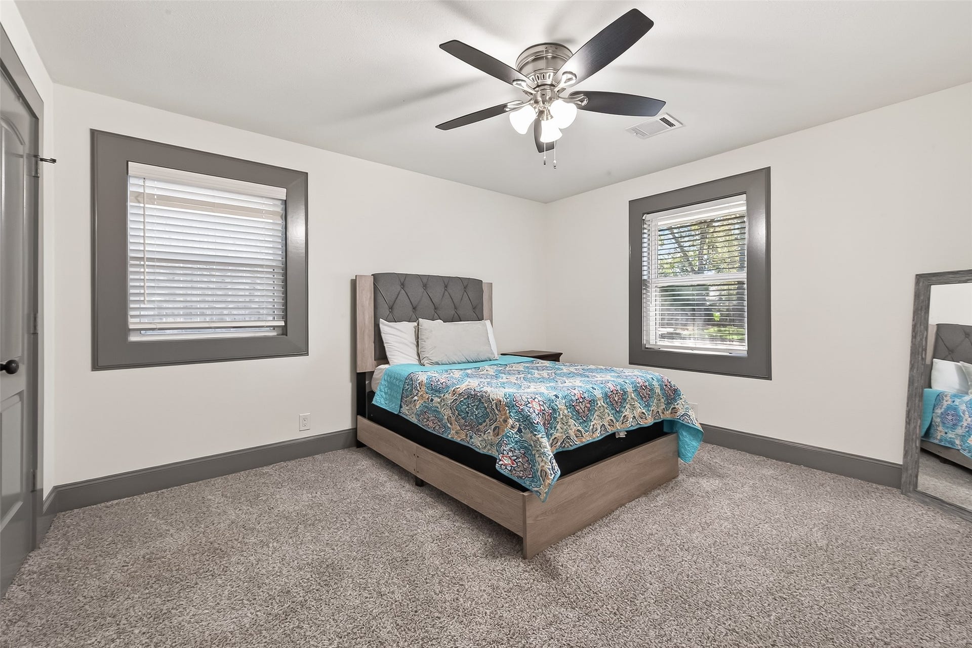 10054 Cedardale Drive, Houston, TX 77055 This bedroom is cozy, with a carpeted floor with a modern ceiling fan and two windows for natural light.