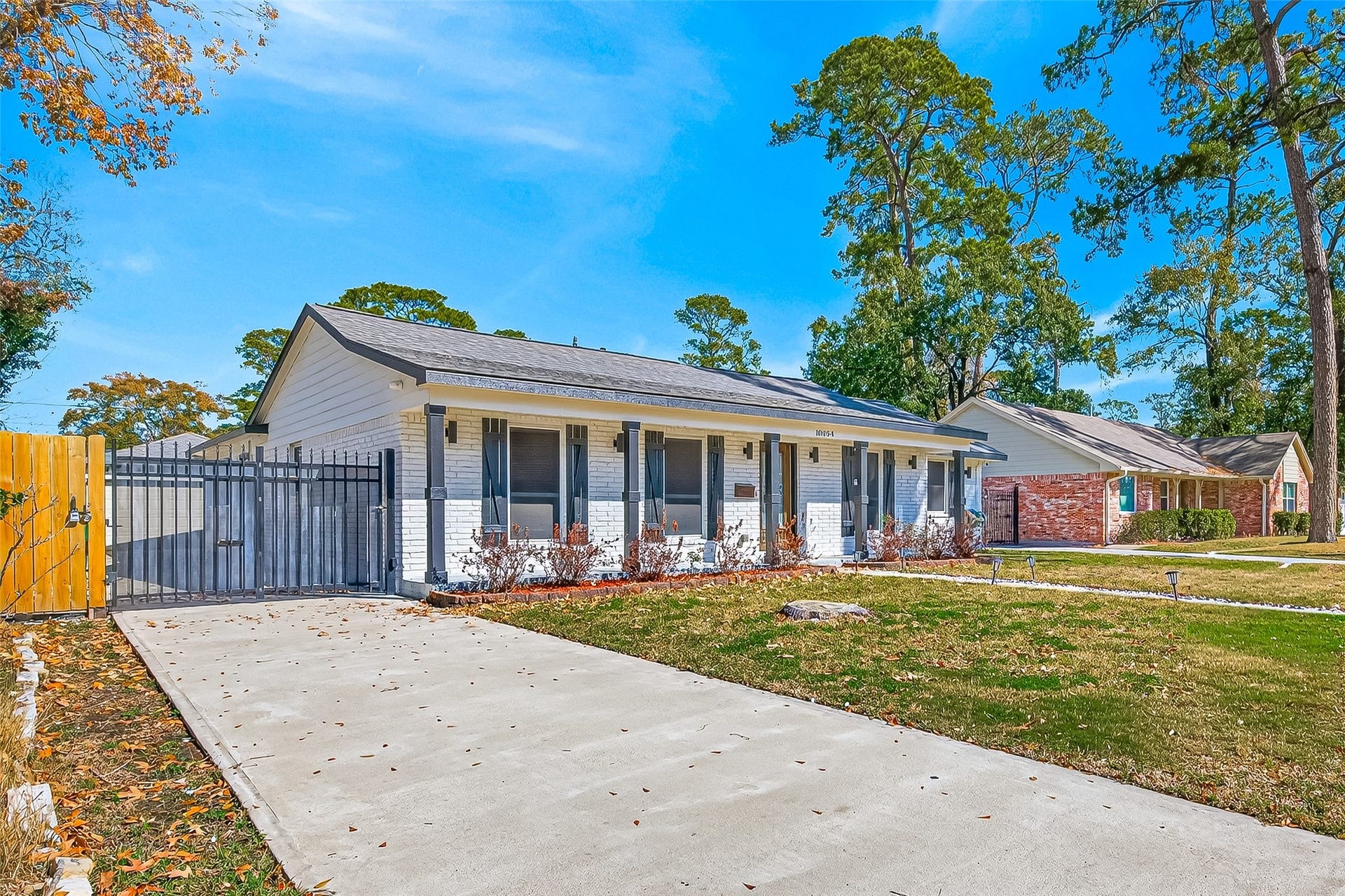10054 Cedardale Drive, Houston, TX 77055 It has a neatly maintained front yard and a long driveway leading to a gated side entrance.