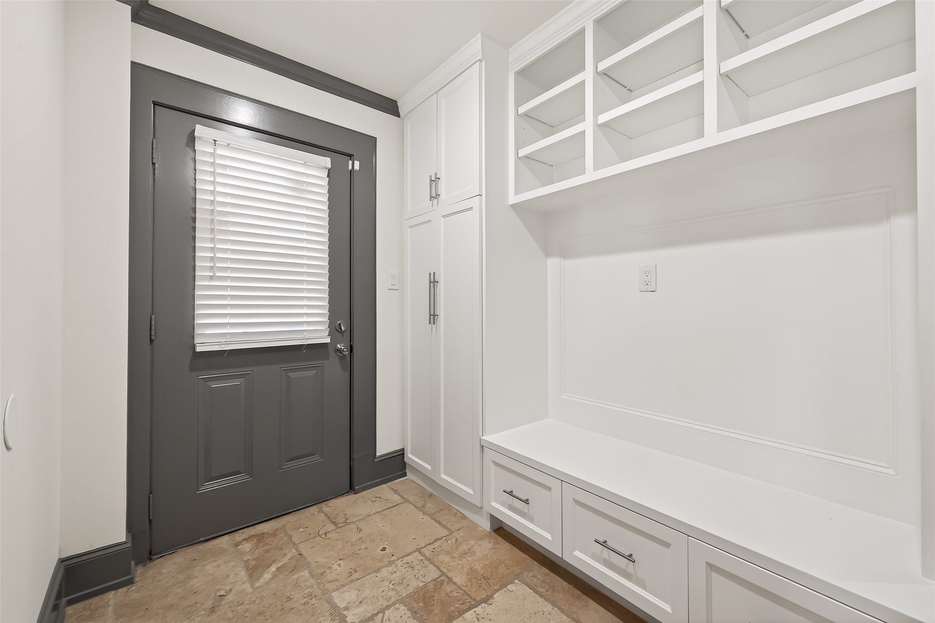 10054 Cedardale Drive, Houston, TX 77055 It features a built-in bench with storage drawers, open shelving above, and a tiled floor, providing a functional entryway space.