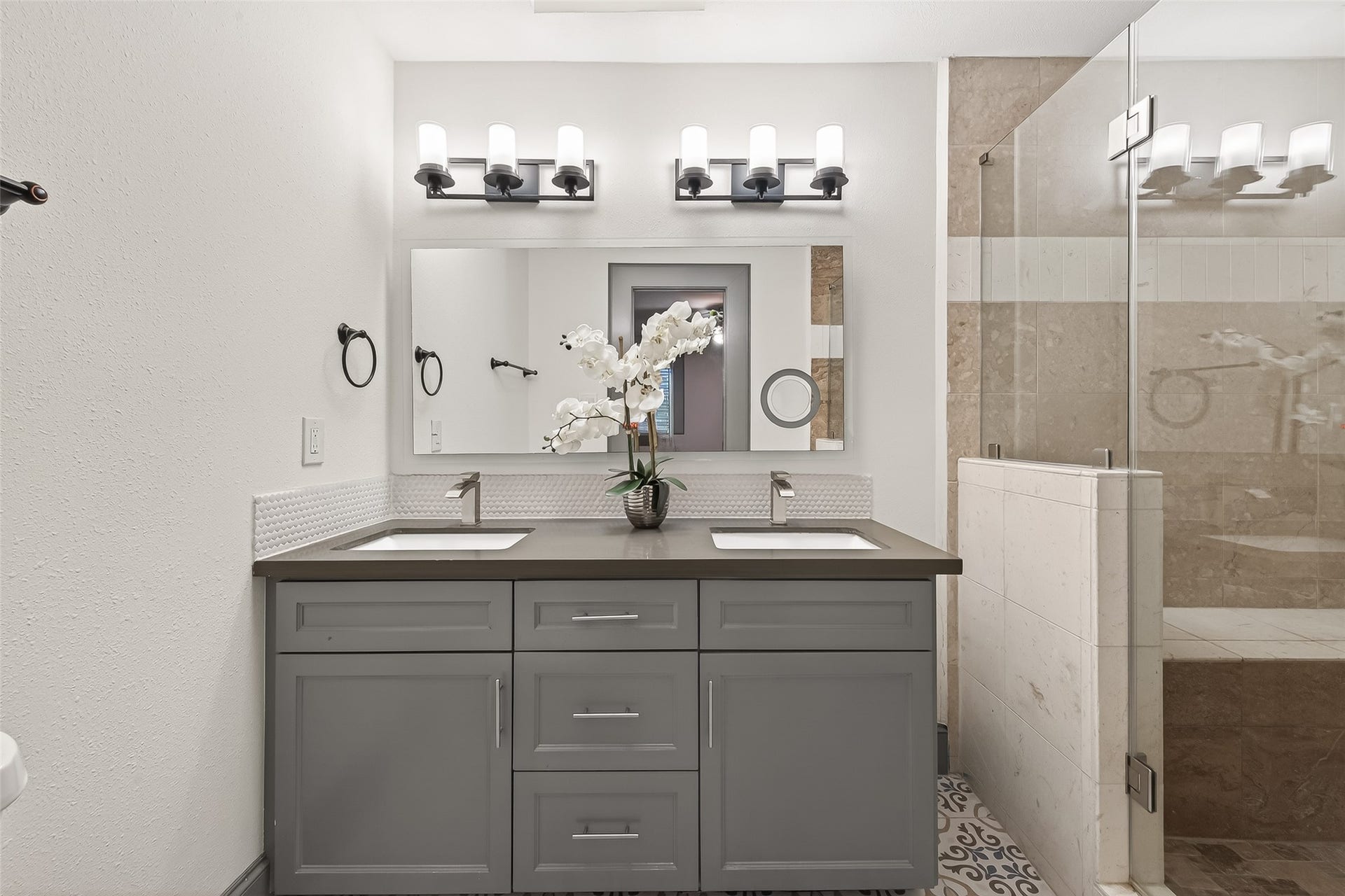 10054 Cedardale Drive, Houston, TX 77055 This bathroom is a modern design with a double vanity, sleek gray cabinets, and elegant lighting fixtures.