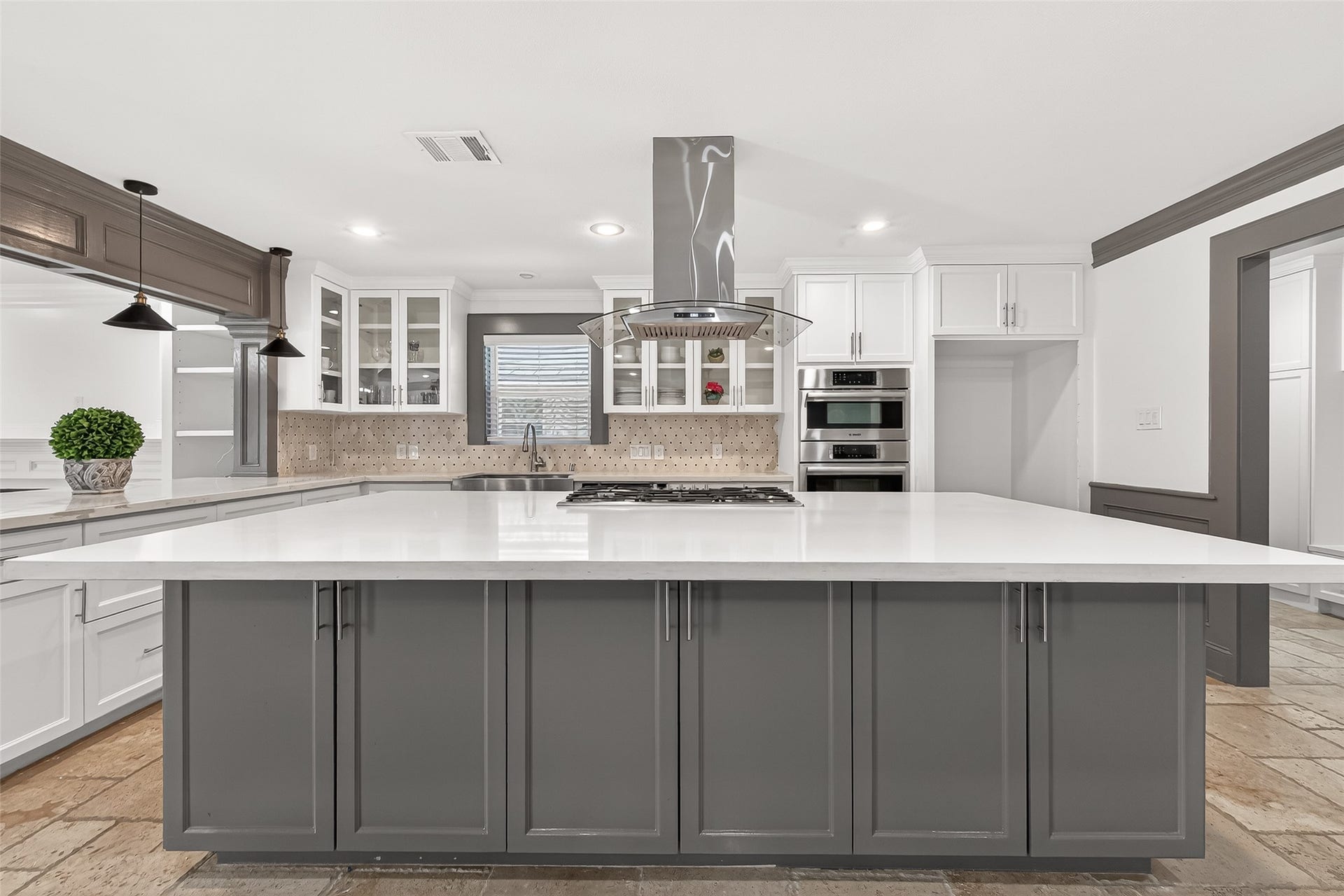 10054 Cedardale Drive, Houston, TX 77055 This modern kitchen features island with sleek gray cabinetry, a white countertop, and a built-in cooktop.