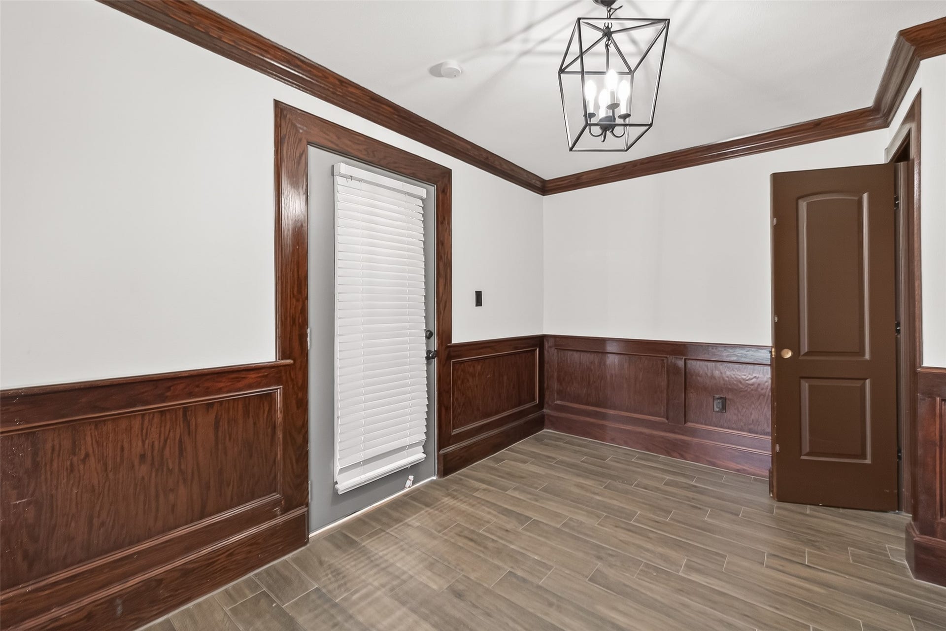 10054 Cedardale Drive, Houston, TX 77055 This room features elegant wood paneling and trim, a modern light fixture, and tile flooring, creating a classic and sophisticated ambiance.