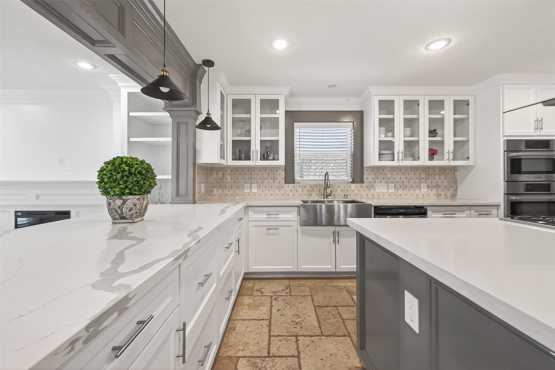 10054 Cedardale Drive, Houston, TX 77055 It has white cabinetry with glass fronts, a farmhouse sink, and a stylish tile backsplash.
