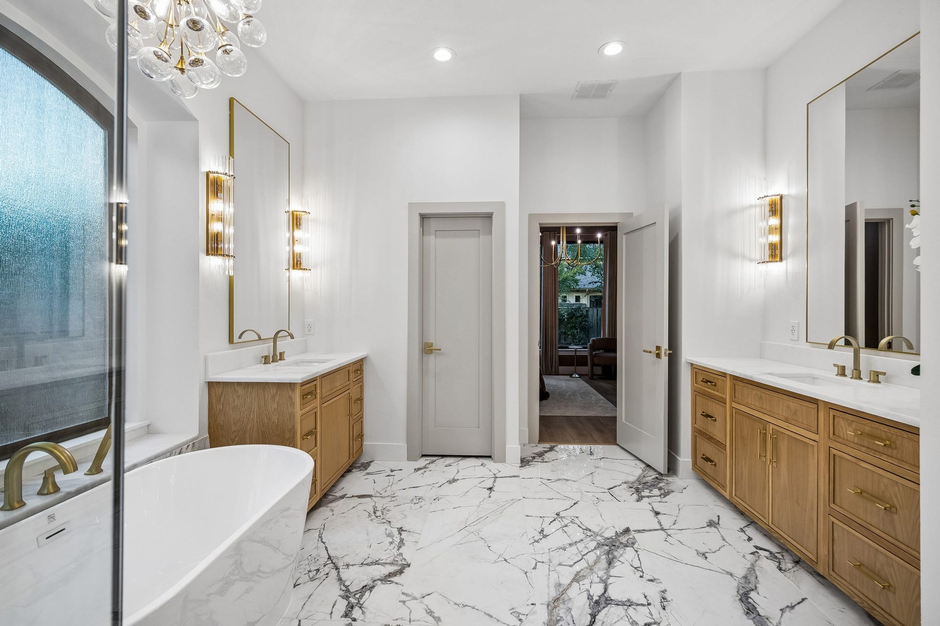 34 N Lansdowne Circle, The Woodlands, TX 77382 Primary bathroom features porcelain tile flooring, white oak cabinetry, a freestanding tub, designer fixtures and sconces