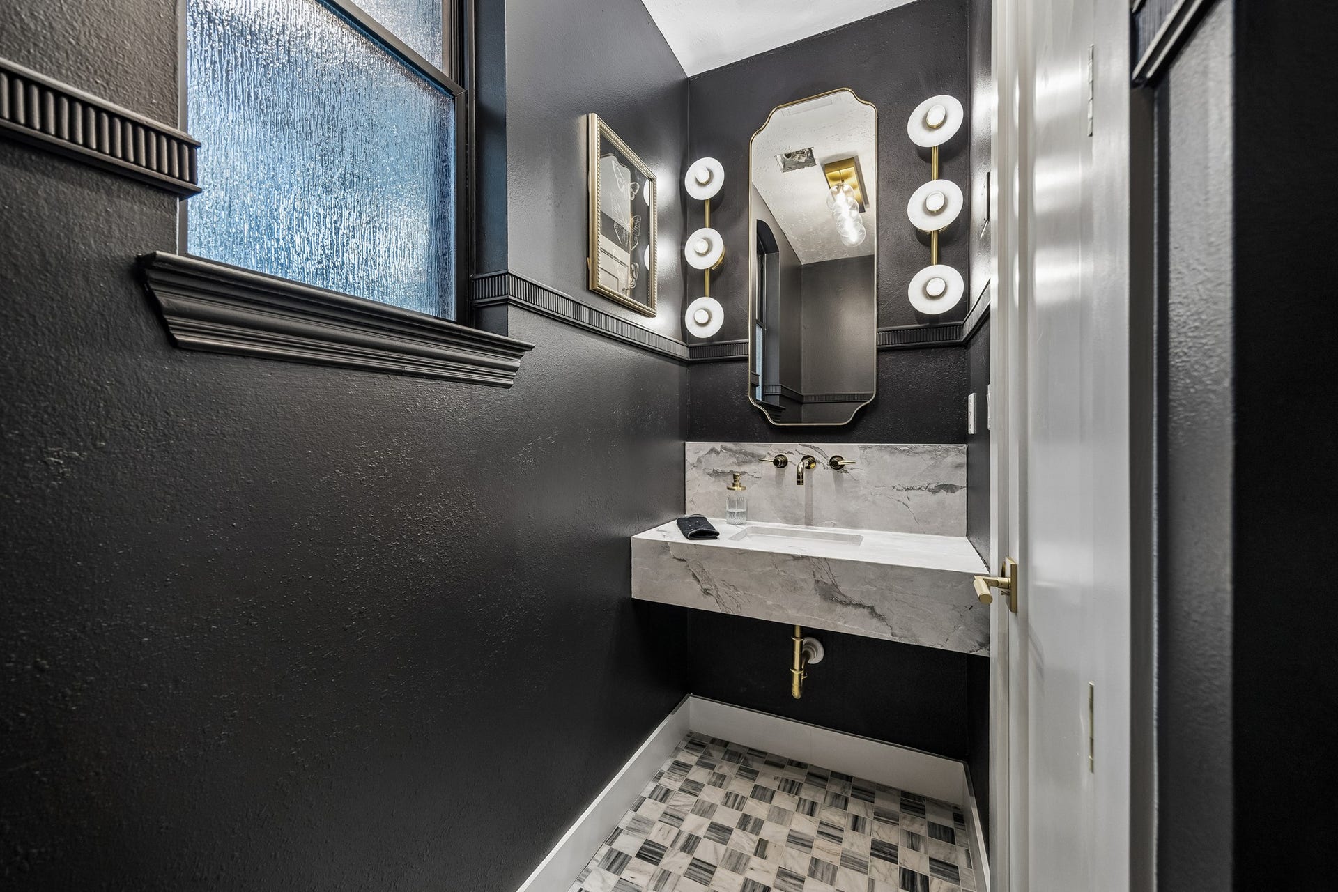 34 N Lansdowne Circle, The Woodlands, TX 77382 Dramatic half bath with a floating marble sink, wall mounted fixture, designer sconces and flooring