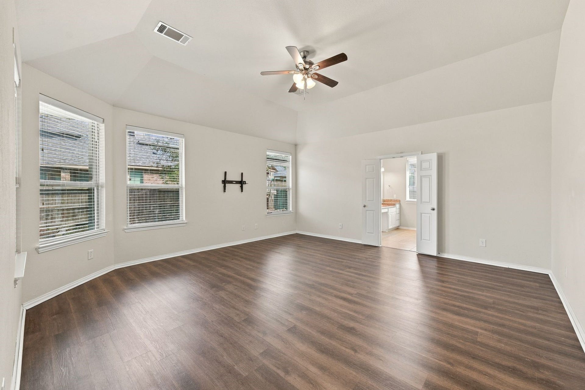 8319 Floating Heart Court, Conroe, TX 77385 Generously sized primary bedroom with rich hardwood floors and an airy vaulted ceiling.