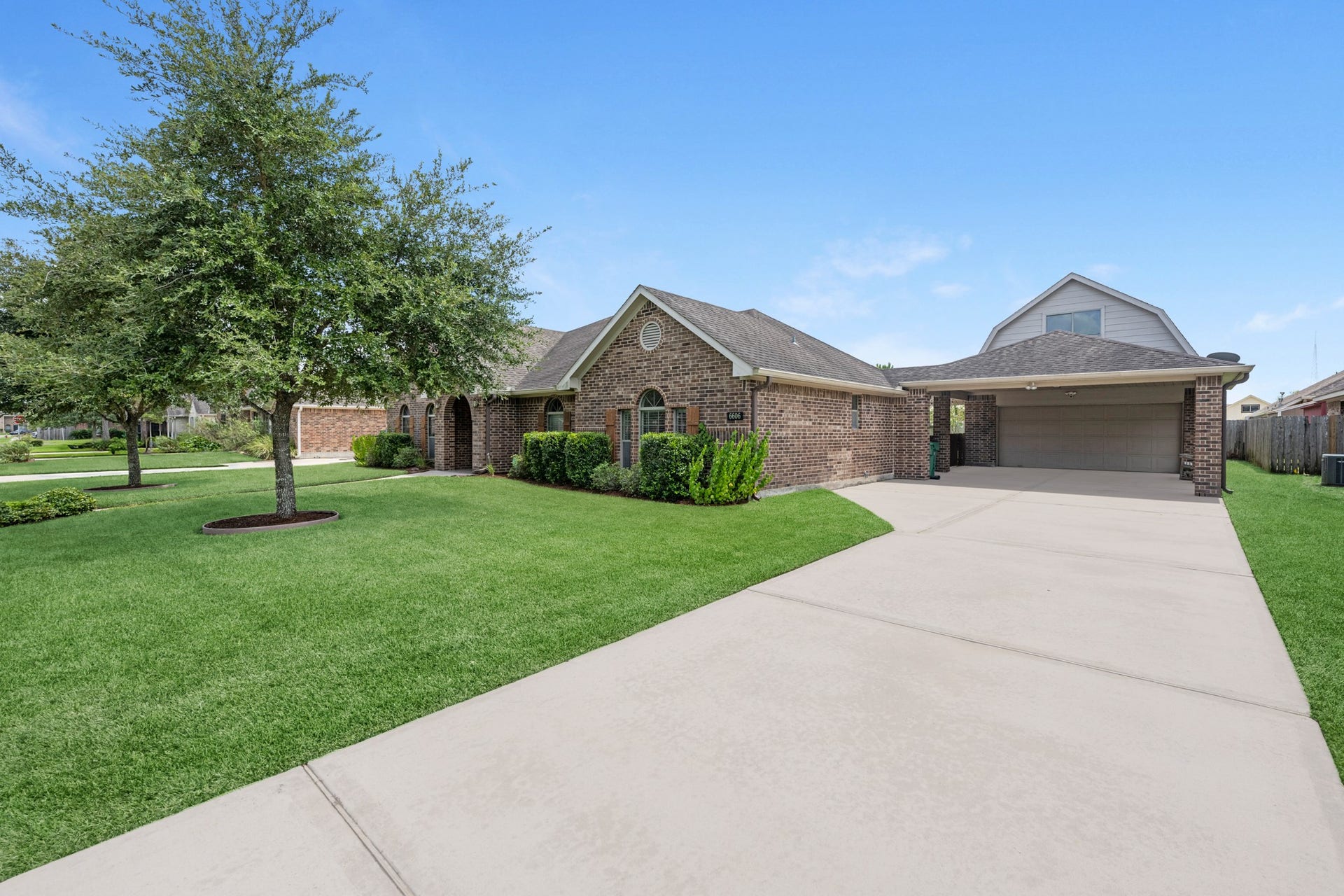 Front exterior featuring a spacious lawn and double wide driveway leading to the detached garage.