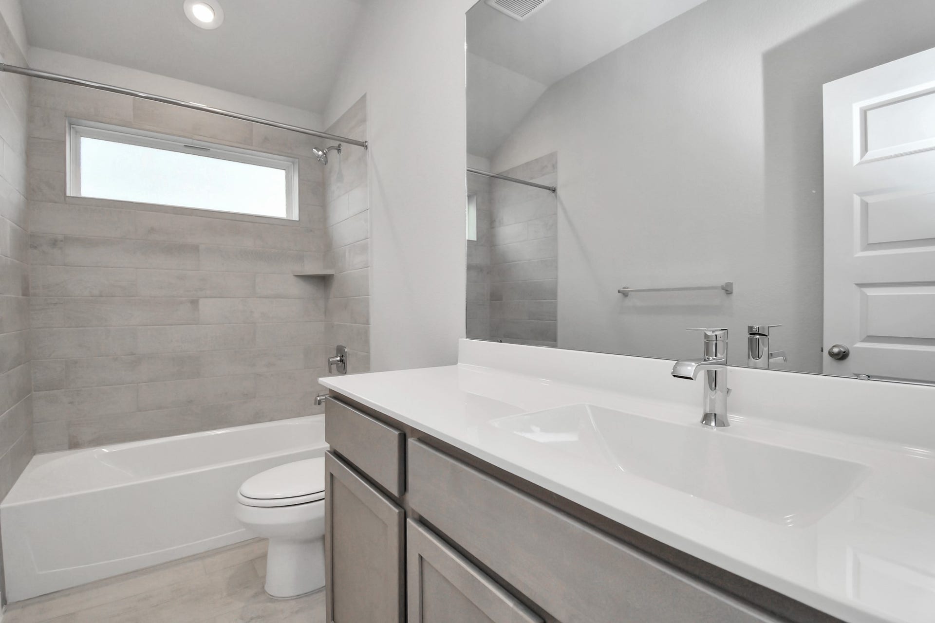 11027 Gardenia Creek Drive, Houston, TX 77044 Secondary bath features tile flooring, bath/shower combo with tile surround, light stained wood cabinets, beautiful light countertop. Sample photo of completed home with similar floor plan. Actual colors and selections may vary.