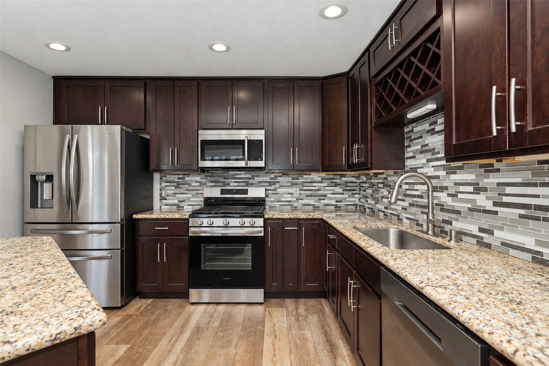 21203 Somerset Park Lane, Katy, TX 77450 Modern kitchen featuring rich dark wood cabinetry, a stylish mosaic tile backsplash, and sleek granite countertops.