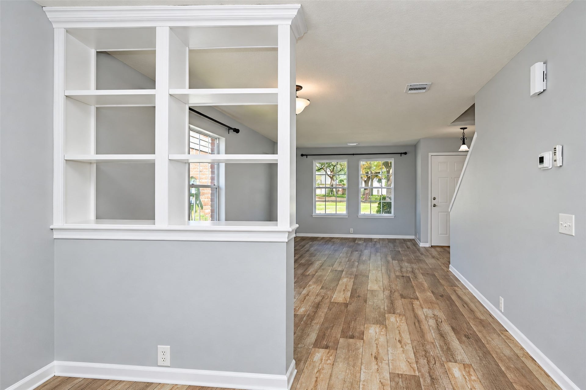 21203 Somerset Park Lane, Katy, TX 77450 Spacious open-concept living area with elegant built-in shelving, abundant natural light from large windows, and stylish wood-look flooring.