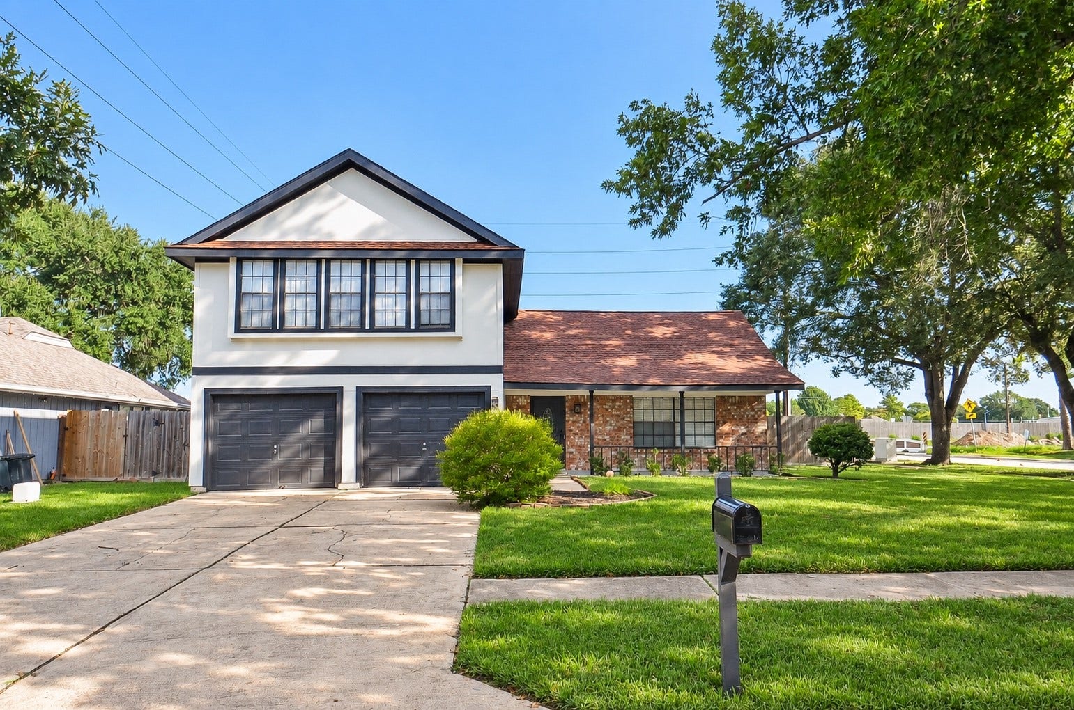 Welcoming two-story home with classic brick accents, a spacious two-car garage, and a manicured front lawn in a tranquil neighborhood