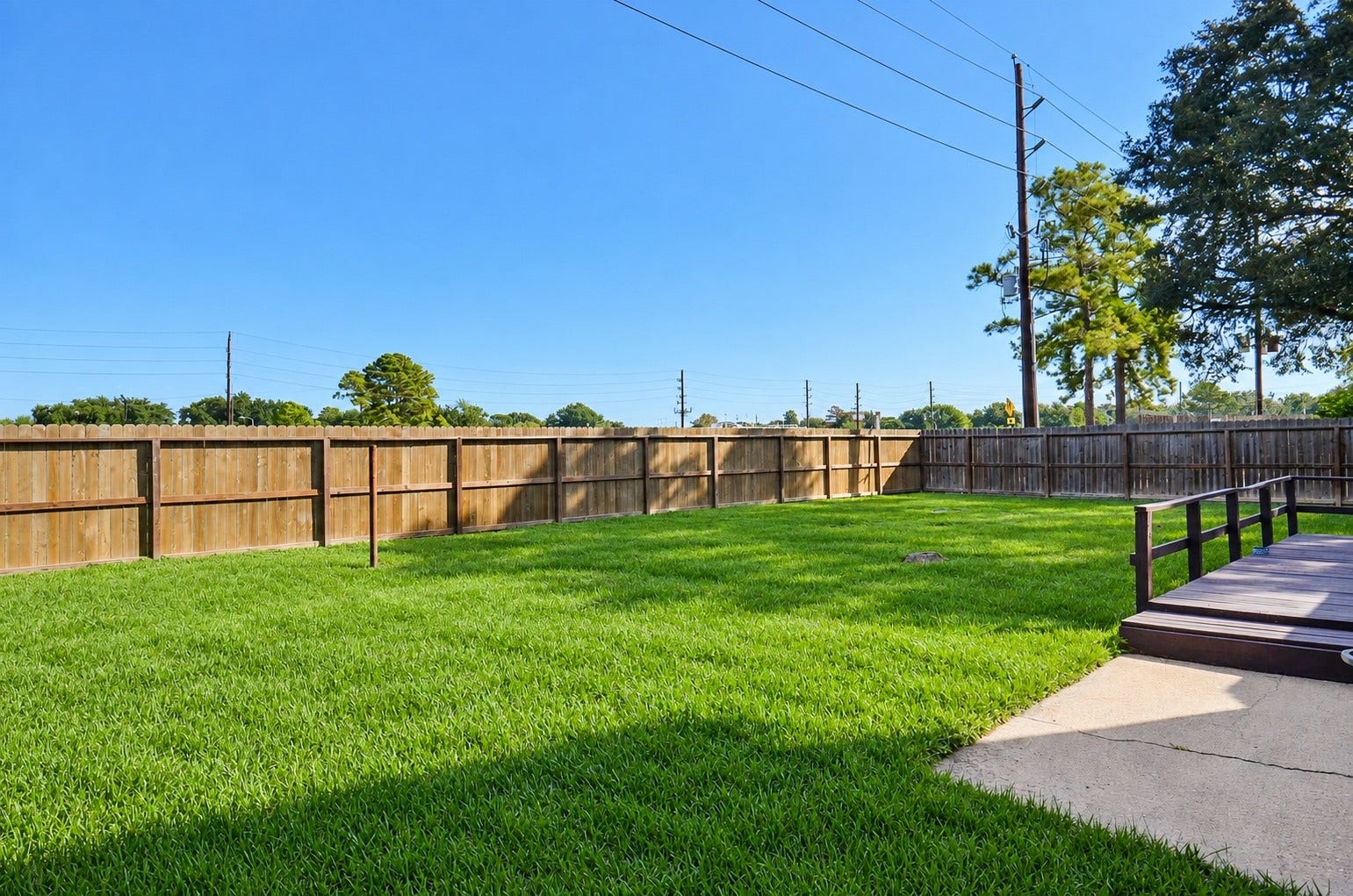 An expansive, fenced backyard with a lush green lawn offers the perfect setting for outdoor activities and ultimate relaxation.