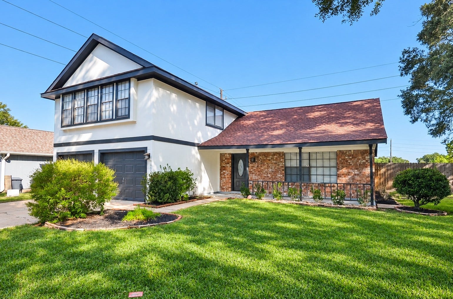 Charming two-story home with a classic brick facade, featuring a well-maintained lawn and inviting front porch.
