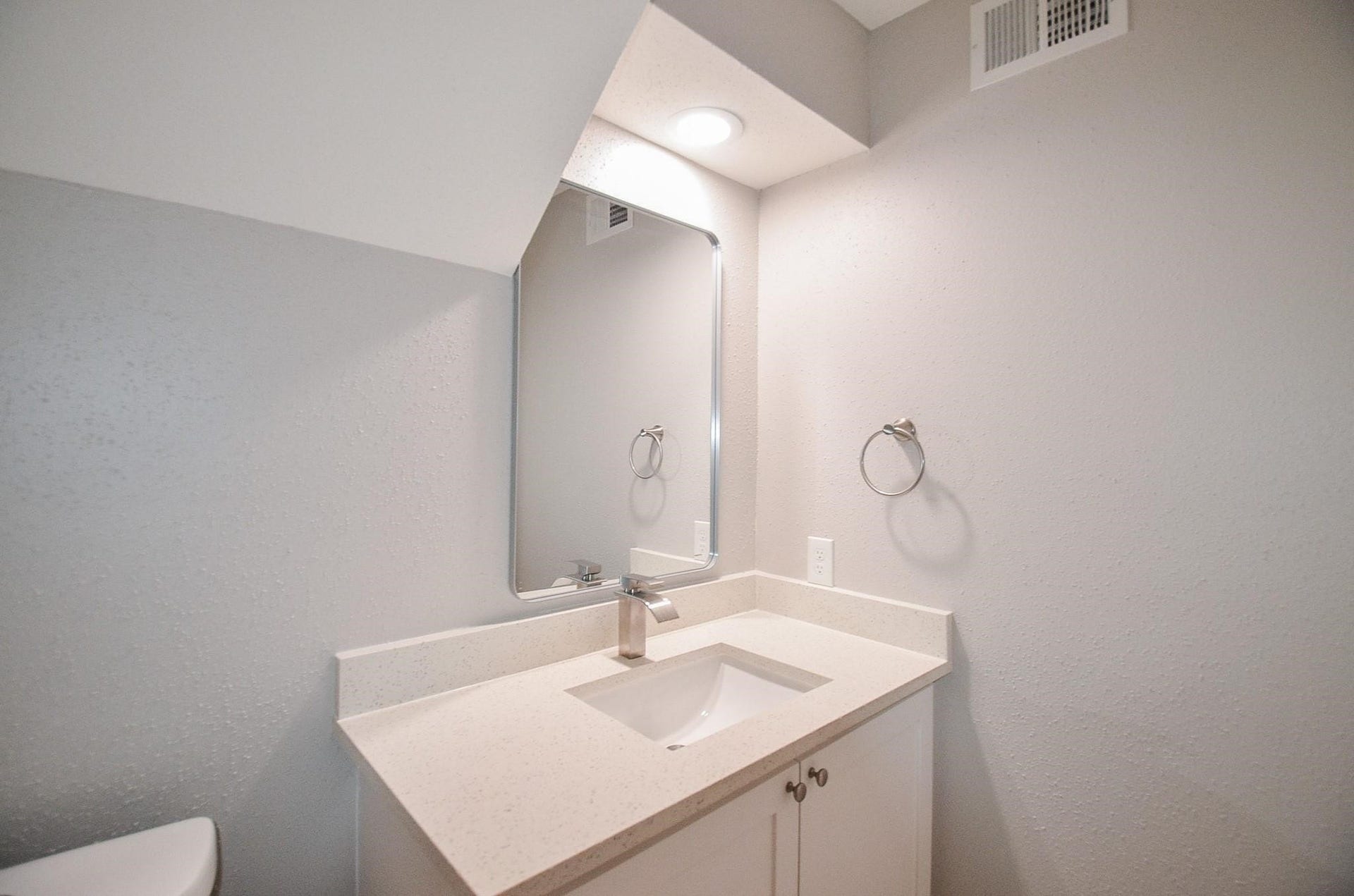 Bright and modern bathroom featuring a sleek vanity with a quartz countertop, polished fixtures, and an elegant mirror.