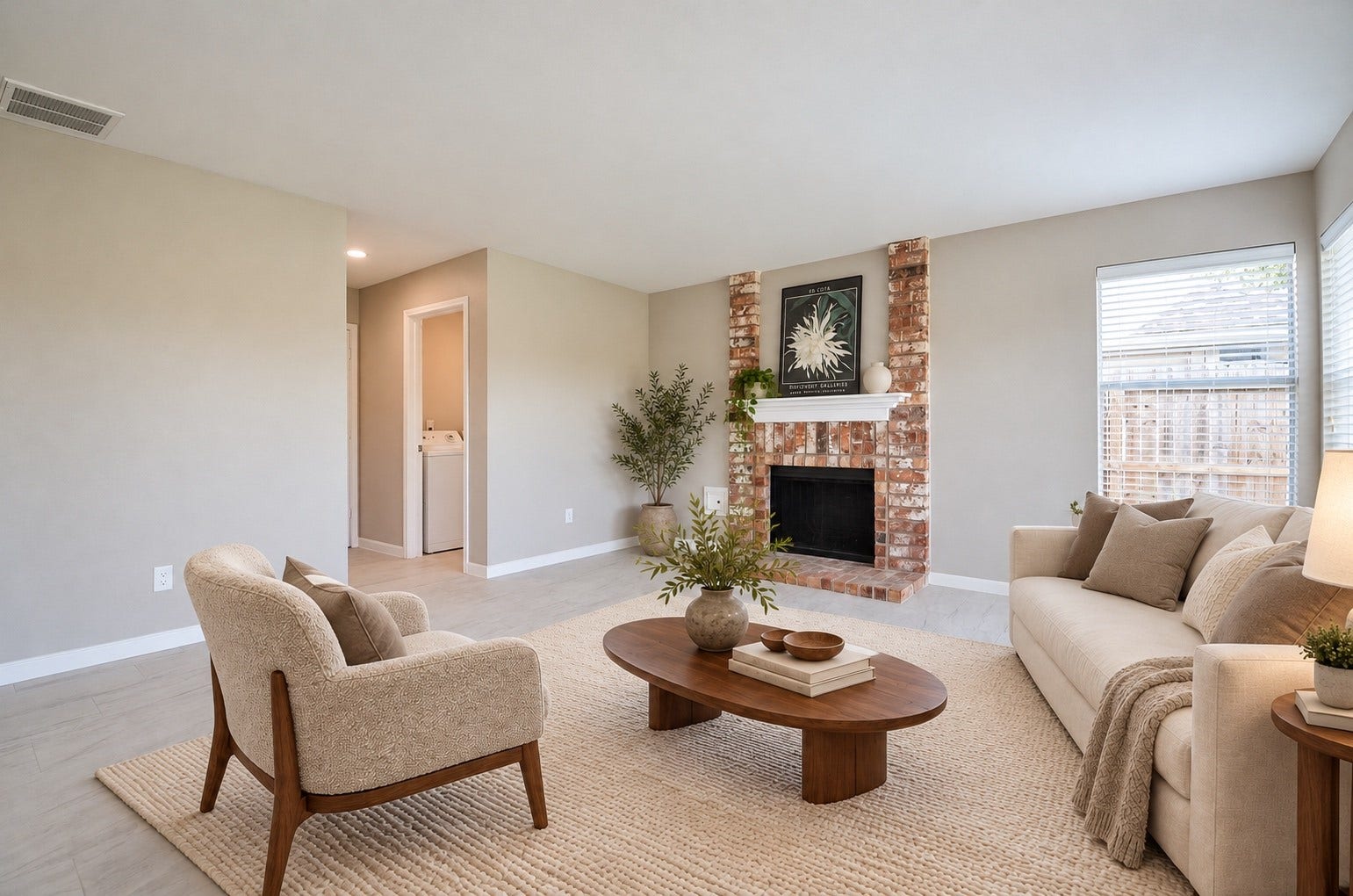 A light-filled living room with a charming brick fireplace and soft neutral tones creates a warm, welcoming space to relax and gather.
