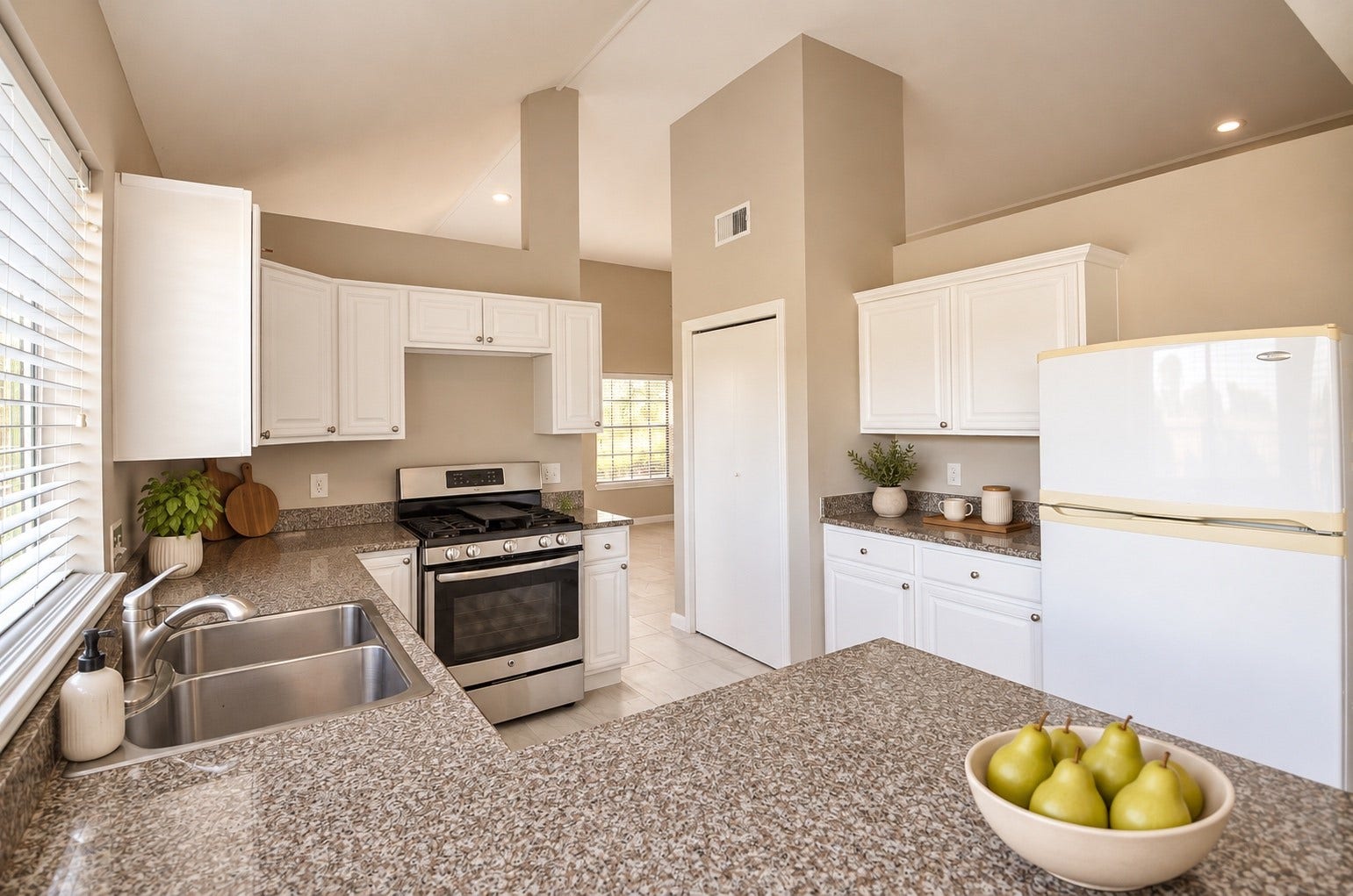 Enjoy a light-filled kitchen featuring polished granite surfaces, sleek stainless steel appliances, and abundant white cabinets for convenient storage and meal preparation.