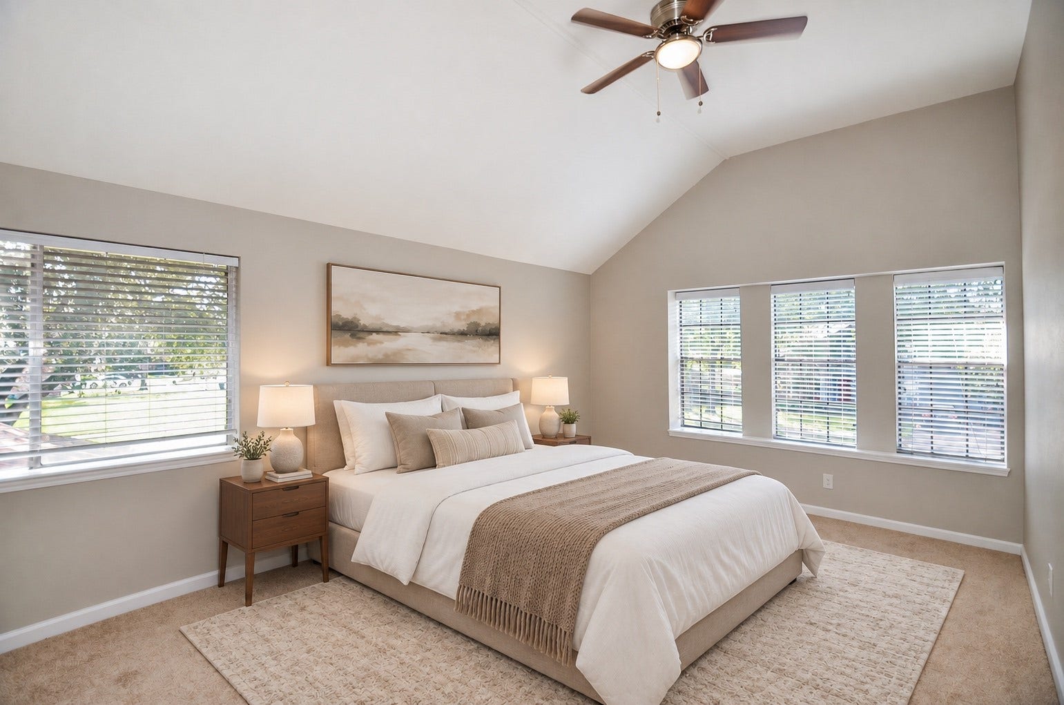 Experience tranquility in this spacious bedroom, featuring a vaulted ceiling, large windows that flood the room with natural light, a cozy bed, and elegant decor.