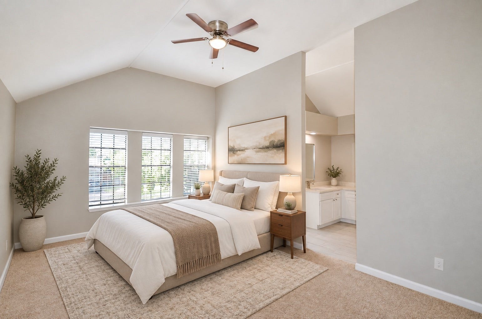 Spacious and serene bedroom with vaulted ceilings, ample natural light, and cozy neutral tones, featuring an elegant adjoining vanity area.