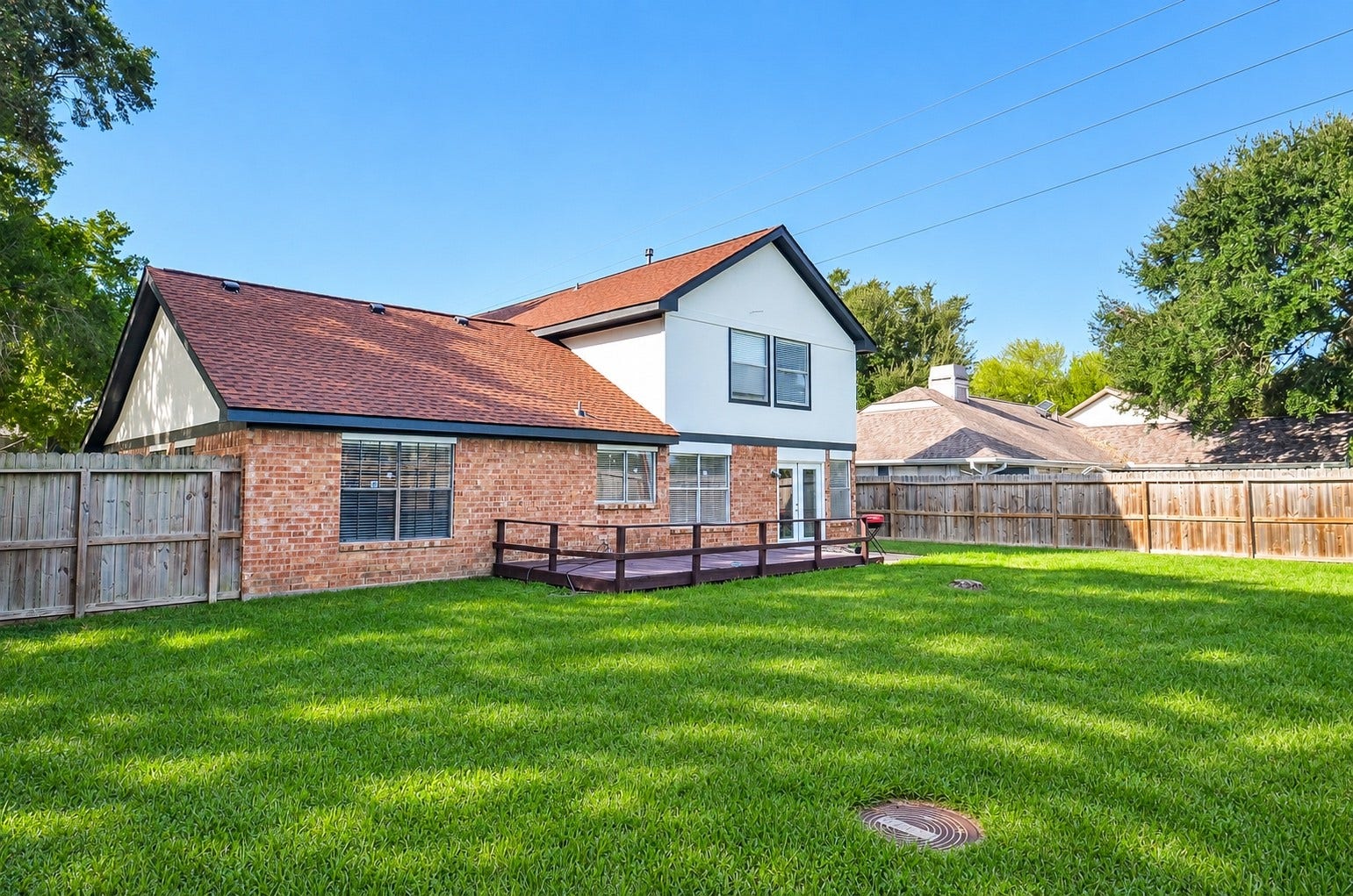 Charming two-story home with a spacious fenced backyard and a cozy wooden deck, perfect for outdoor gatherings and relaxation.