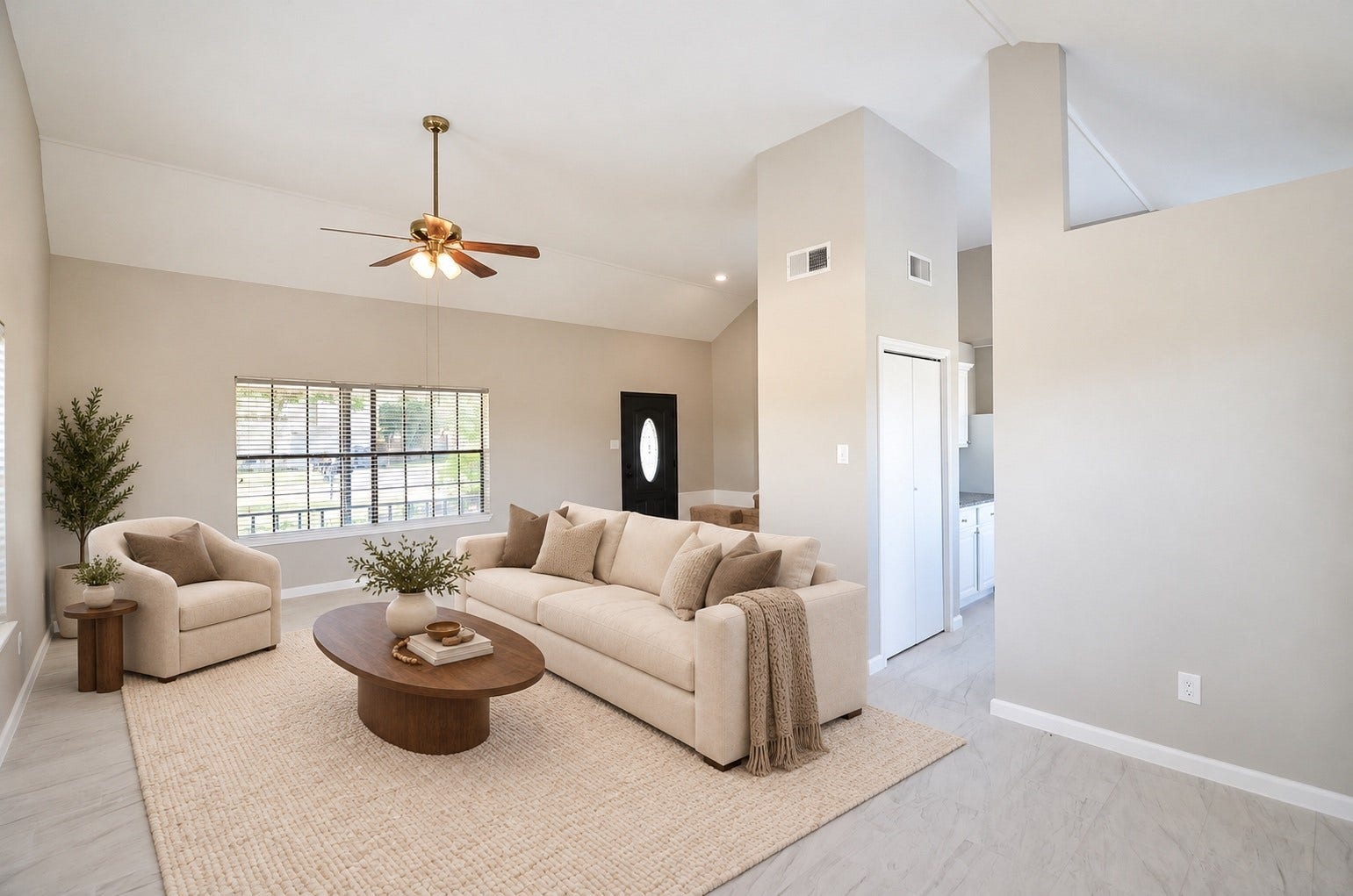 Bright and spacious living area with high ceilings, modern ceiling fan, large windows, and elegant tile flooring.