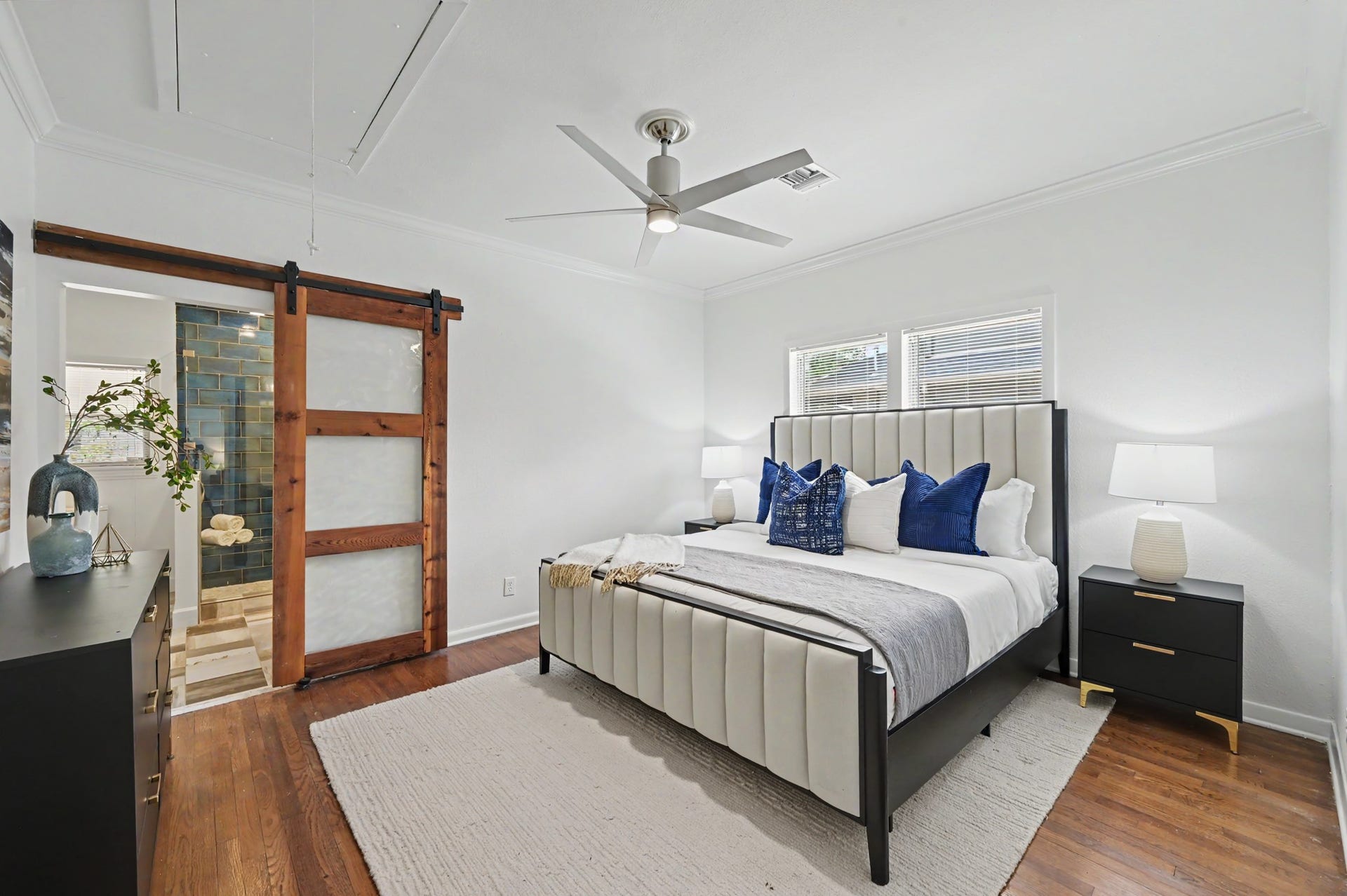 807 Key Street, Houston, TX 77009 Primary bedroom featuring hardwood floors, crown molding, ceiling fan, and a distinctive sliding barn door leading to the en-suite bath.