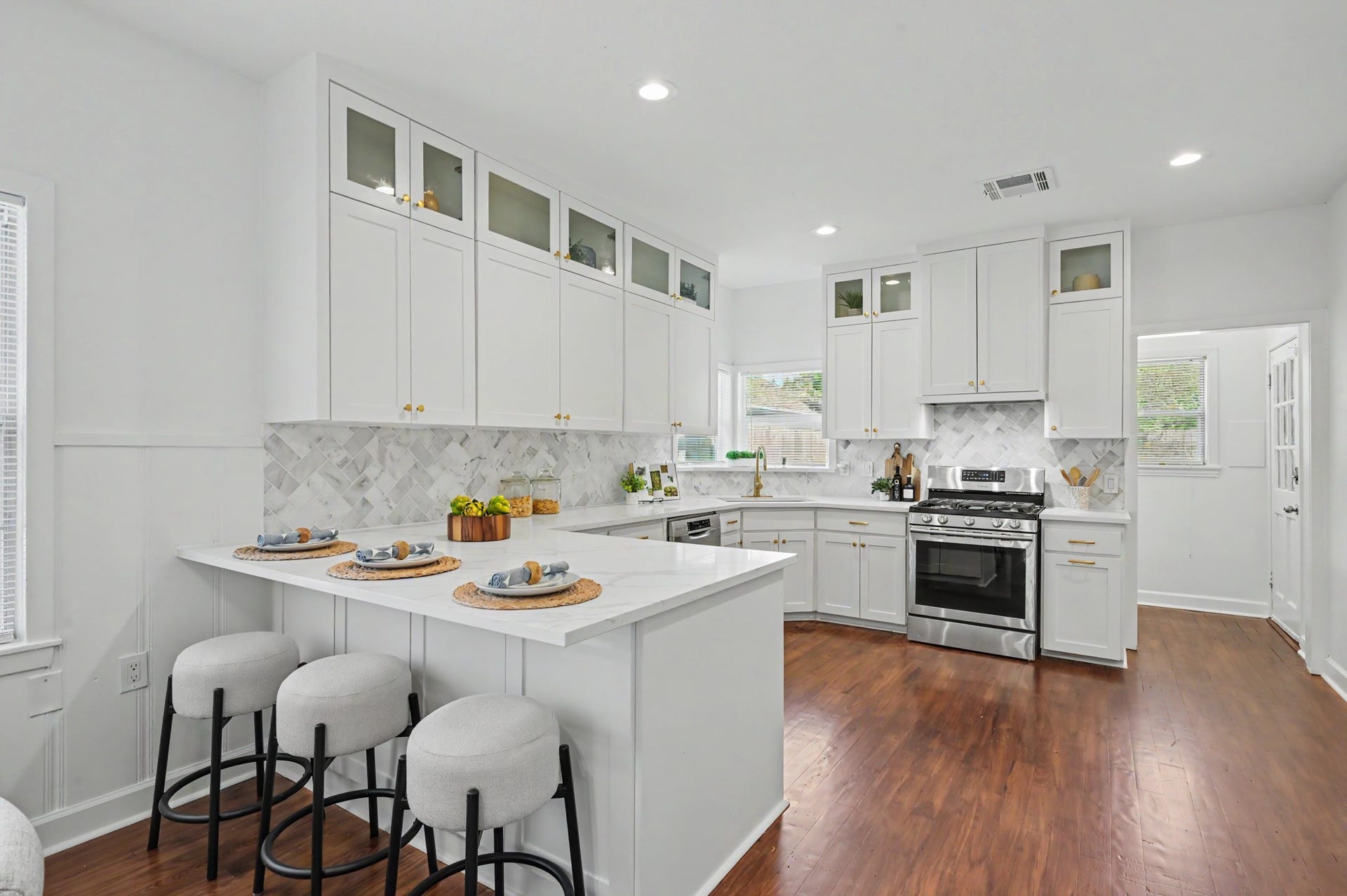 807 Key Street, Houston, TX 77009 White cabinetry, quartz countertops, stainless steel appliances, brass hardware, and a patterned marble tile backsplash.