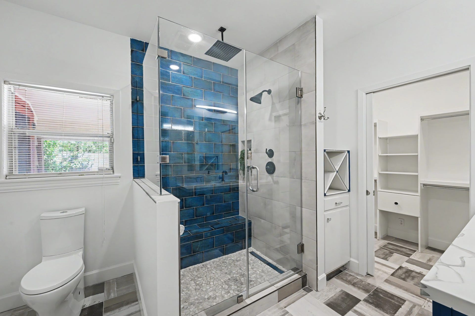 807 Key Street, Houston, TX 77009 Striking walk-in shower with frameless glass enclosure, rainfall showerhead, built-in niche, and contrasting blue accent tile.